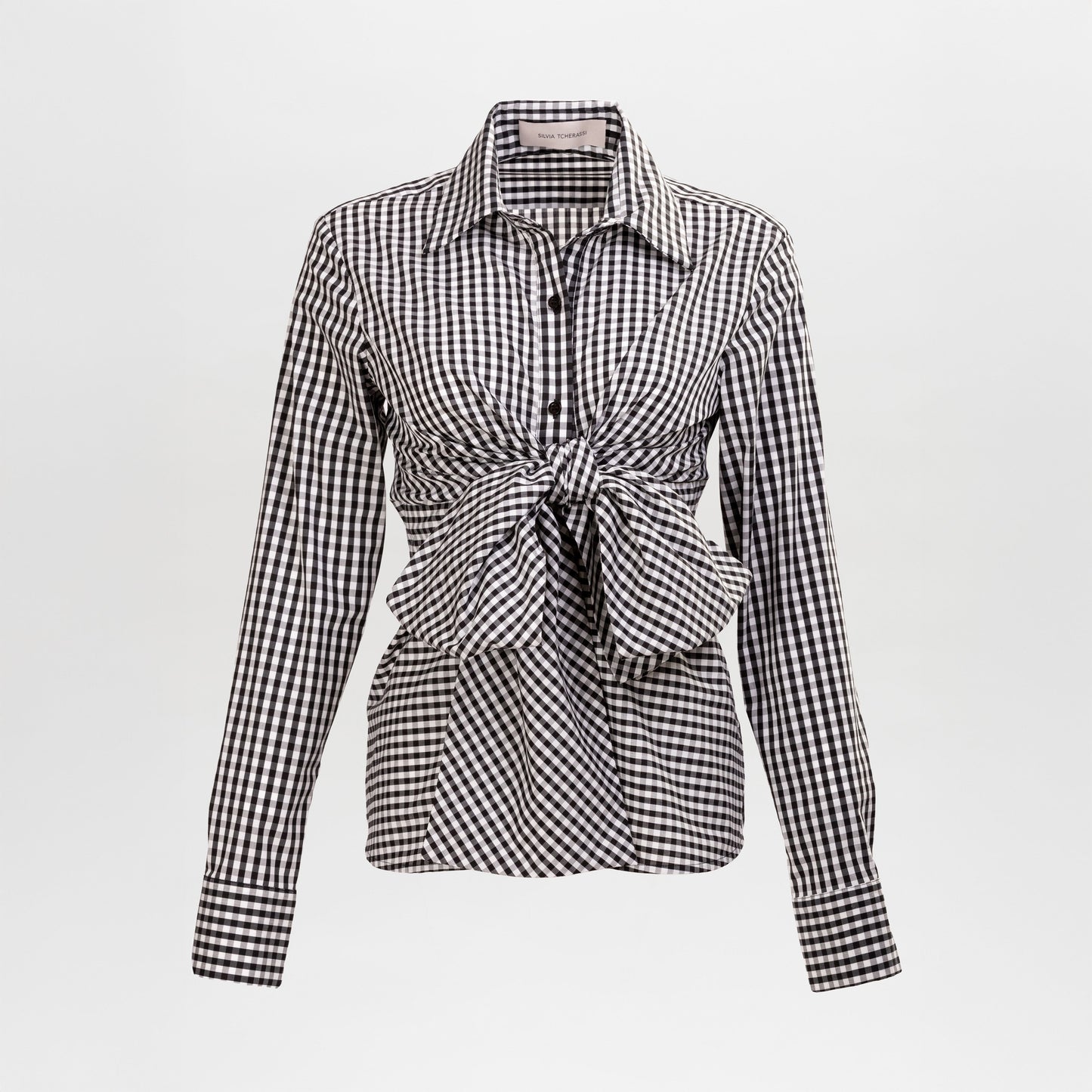 The Mercury Blouse by SVT DESIGNS is a black and white gingham long-sleeve button-up shirt with a classic collar and an oversized front knot at the waist, shown on a plain white background.
