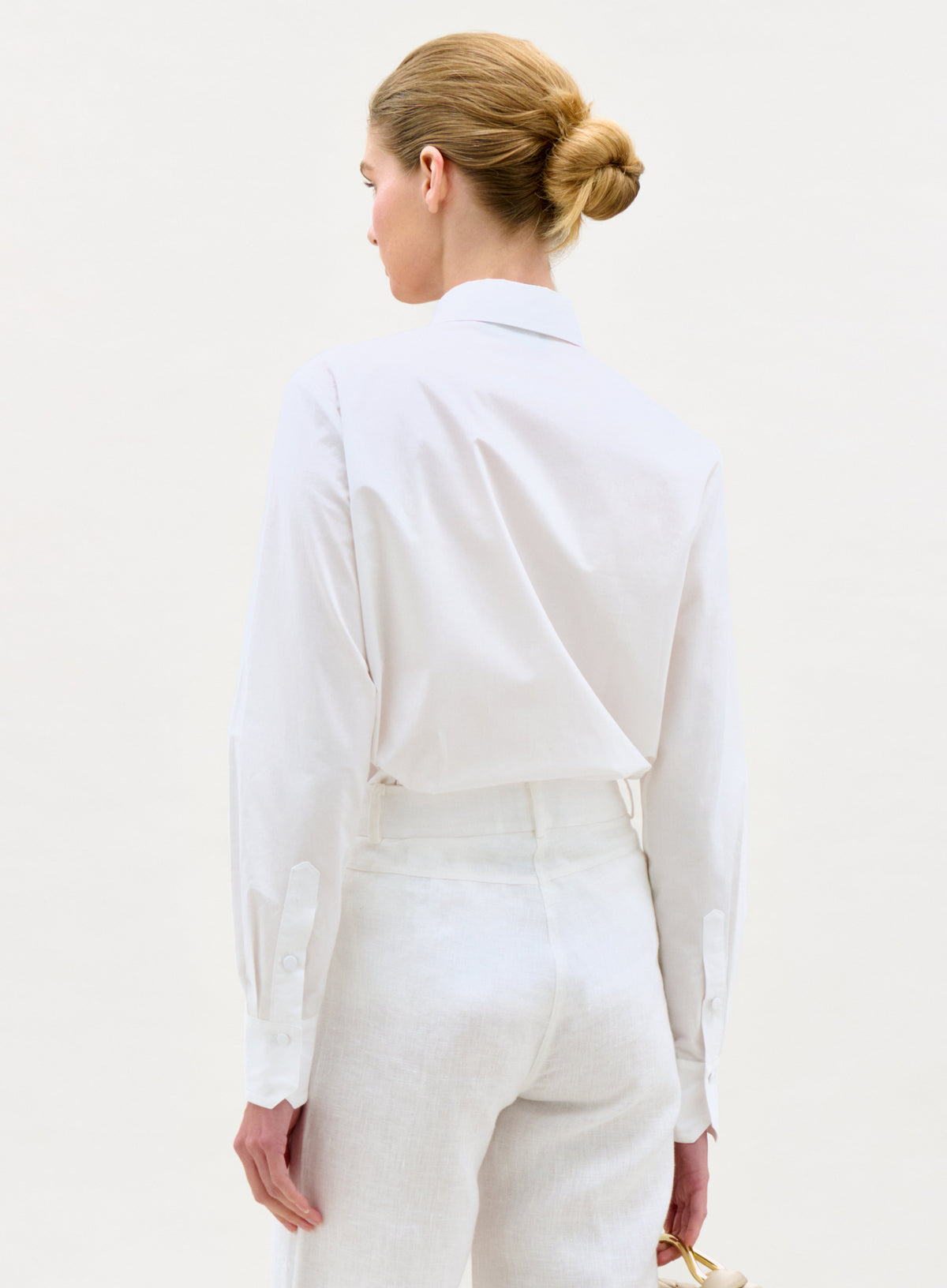Woman wearing a white outfit against a plain background