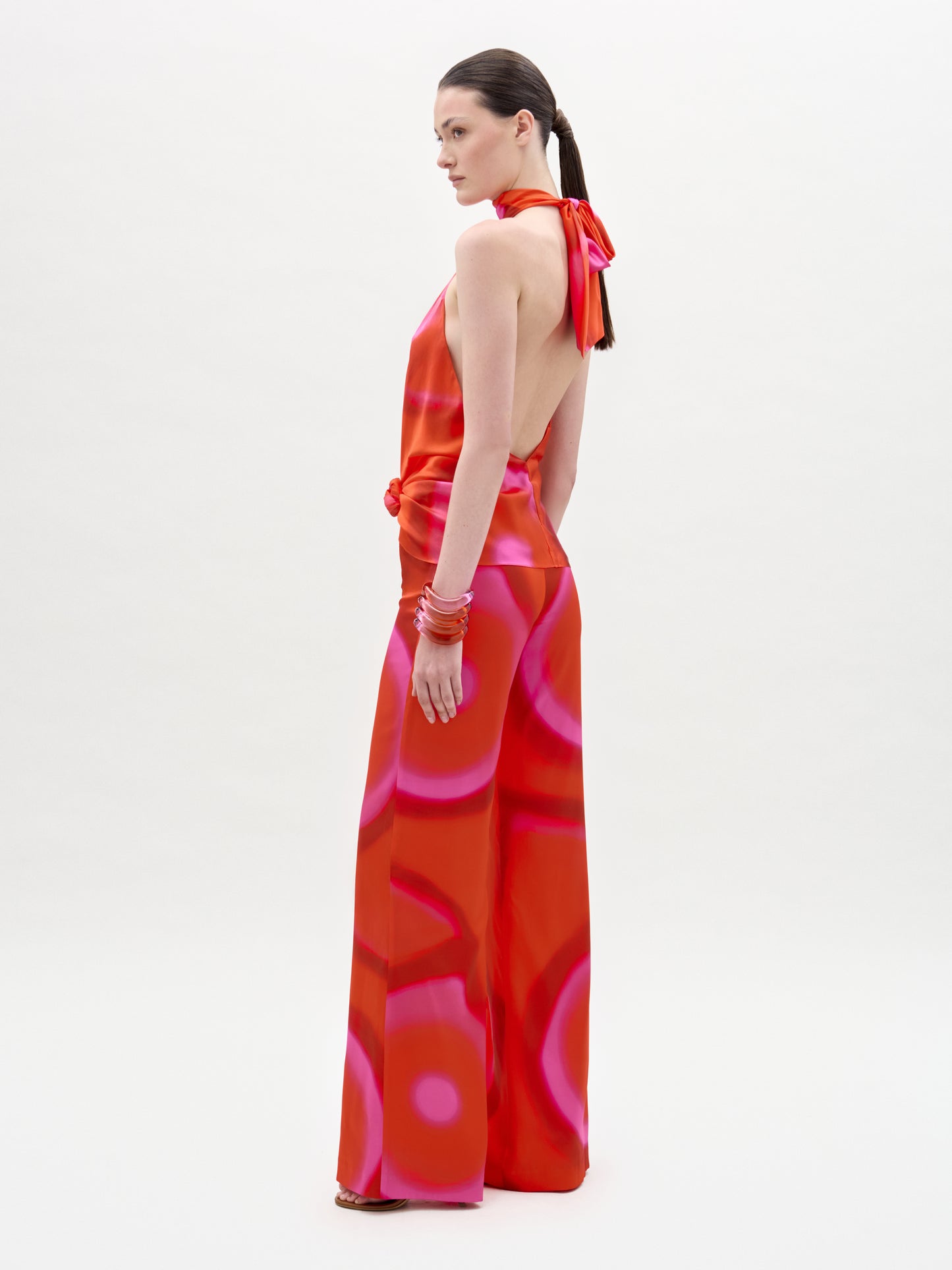 Woman wearing a vibrant red and pink patterned dress on a white background