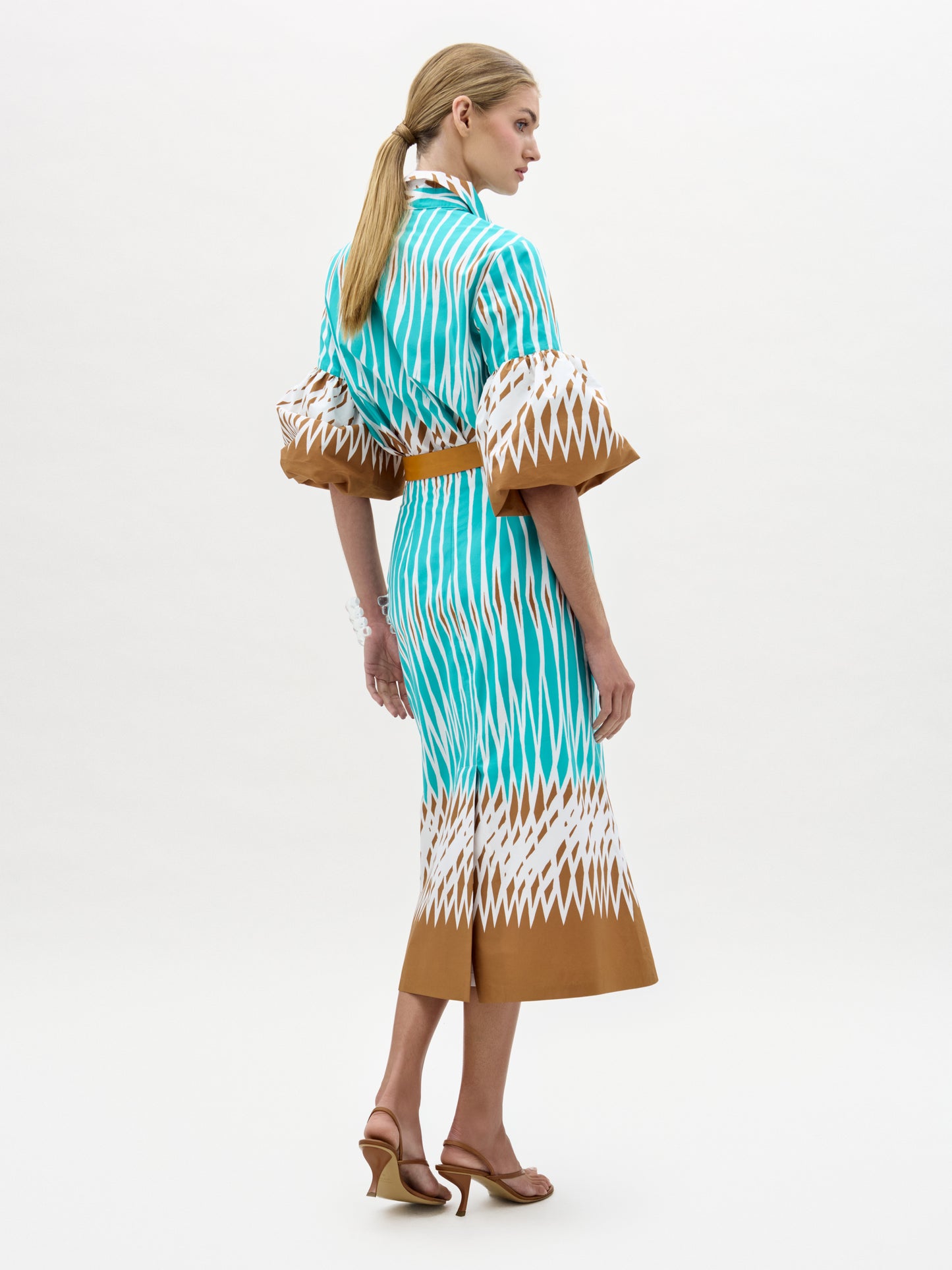 Woman wearing a turquoise and brown patterned dress on a white background