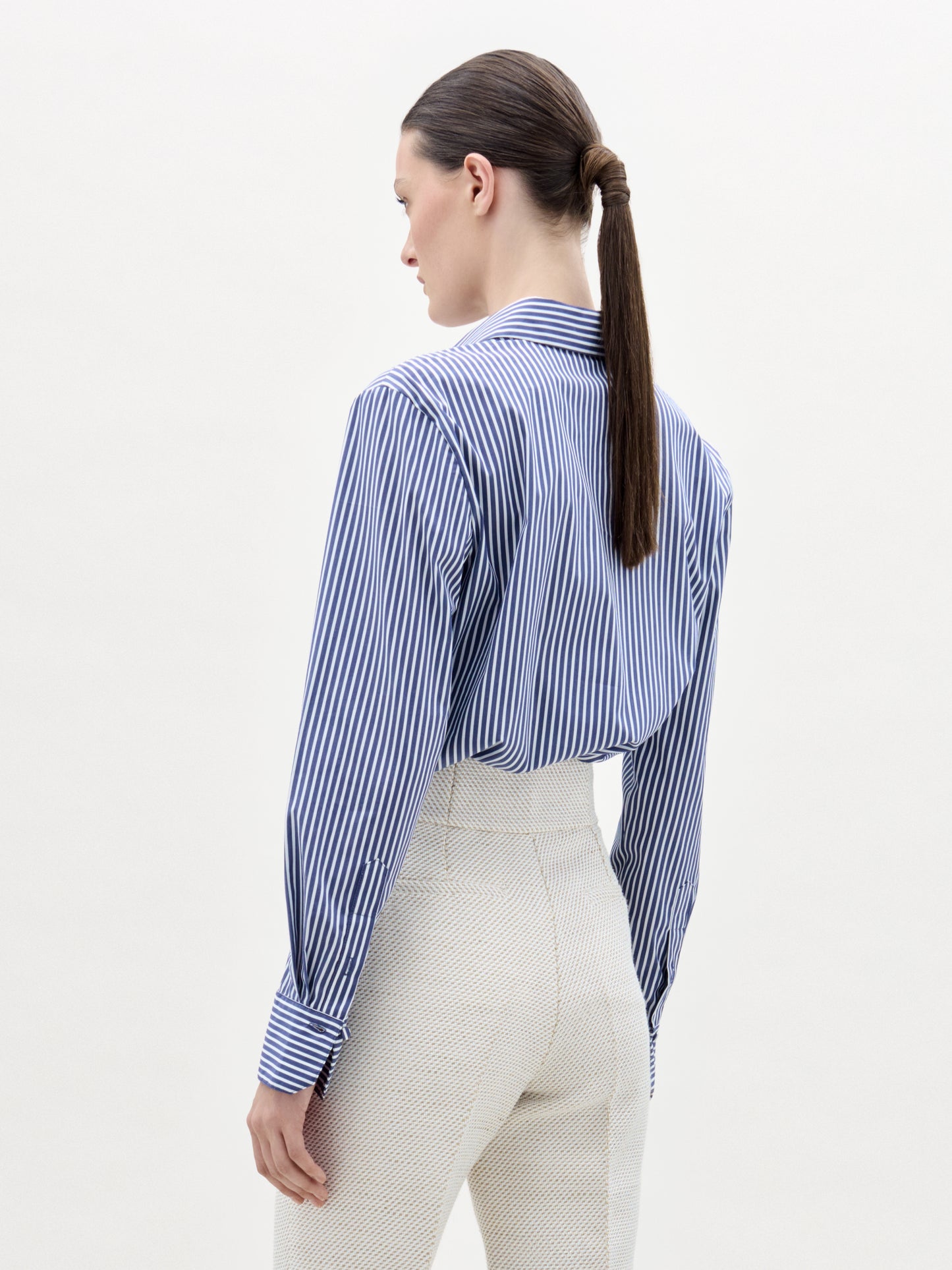 Woman wearing a blue and white striped shirt with a white background