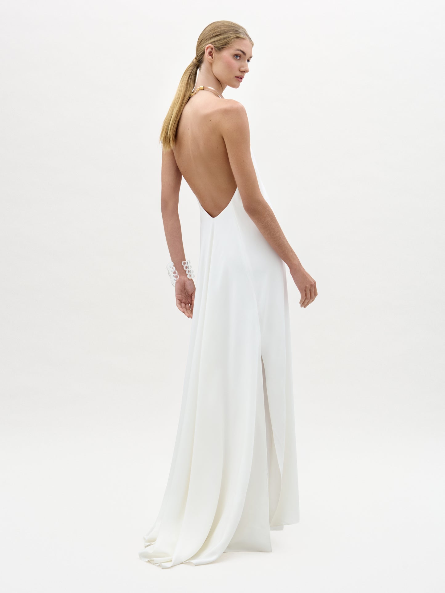 Woman wearing a white open-back dress on a plain background