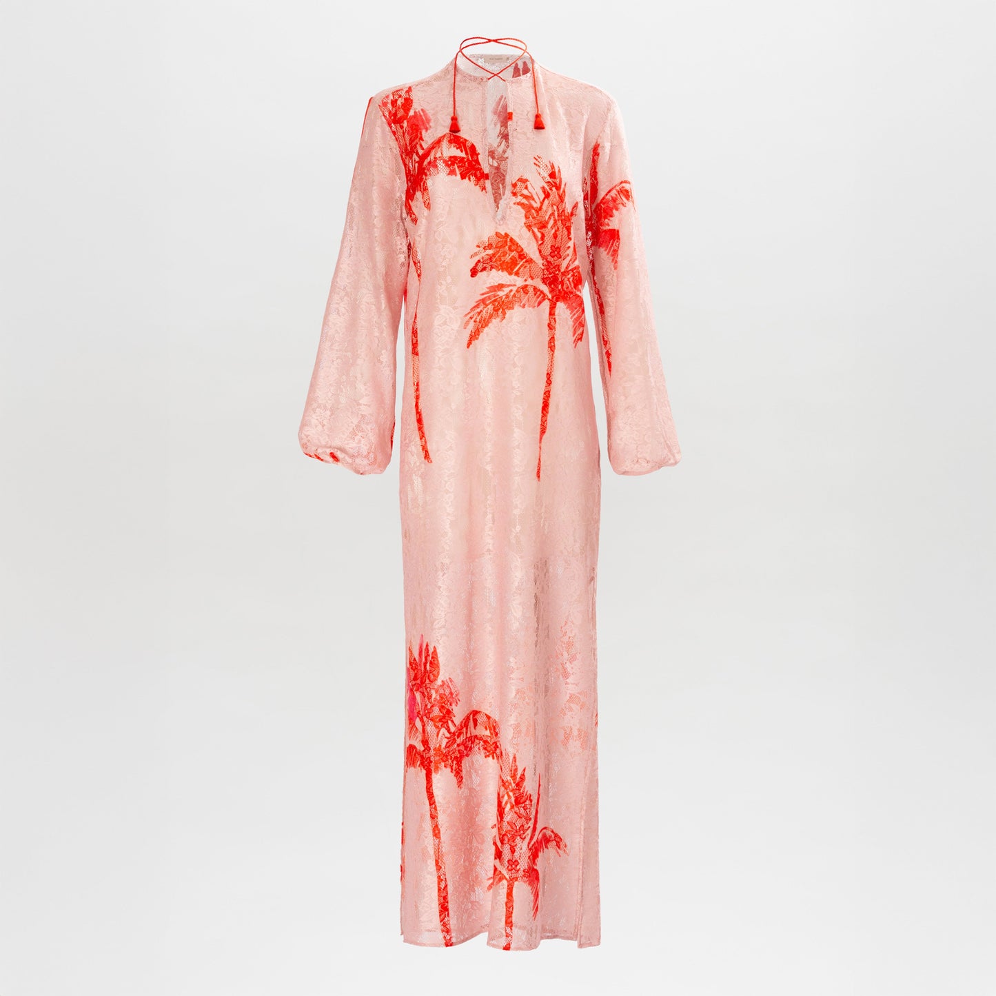 The Mayfair Tunic by SVT DESIGNS is a long-sleeved, floor-length pink dress with a loose fit, high neckline, red palm tree prints on the front, subtle sheen, and a neck tie detail.