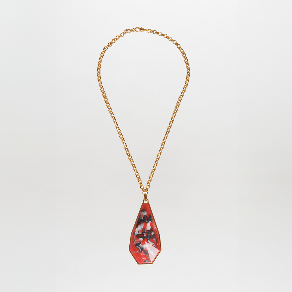 The Ascoli Necklace by SVT DESIGNS features a gold chain with a large, irregular red Petralux® fantasy stone pendant adorned with black and white marbled patterns, shown on a plain white background.
