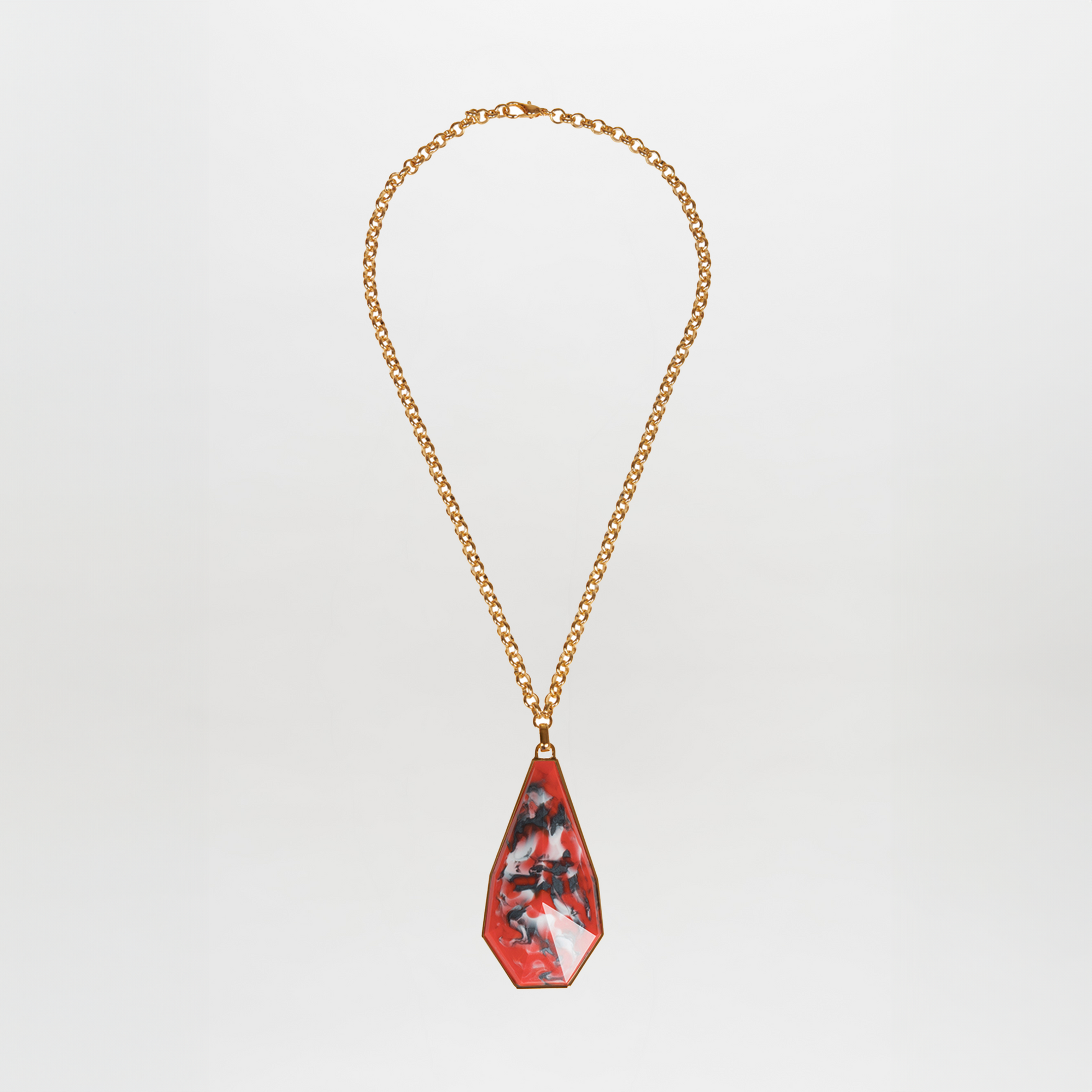 The Ascoli Necklace by SVT DESIGNS features a gold chain with a large, irregular red Petralux® fantasy stone pendant adorned with black and white marbled patterns, shown on a plain white background.