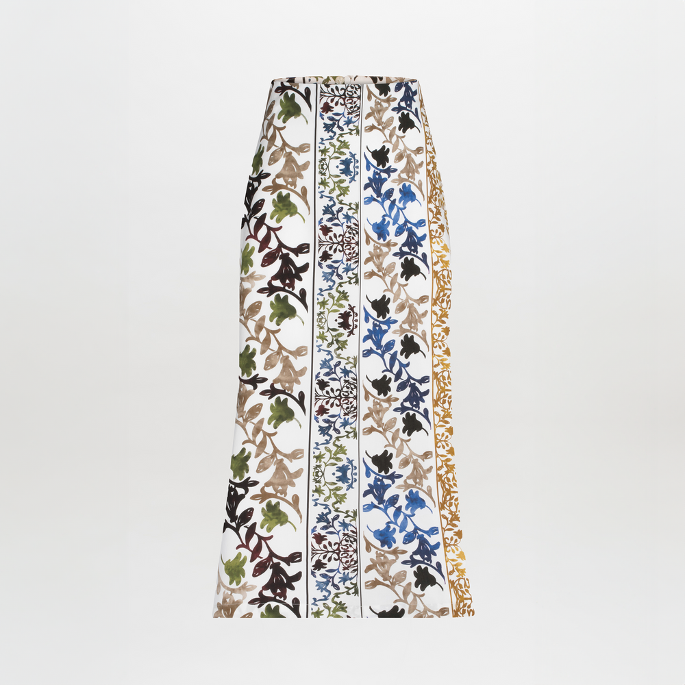 The Atira Skirt by SVT DESIGNS is a chic high-waisted midi skirt with vertical floral patterns in black, green, brown, blue, and gold on a white background, featuring a multicolor abstract print in alternating stripes.