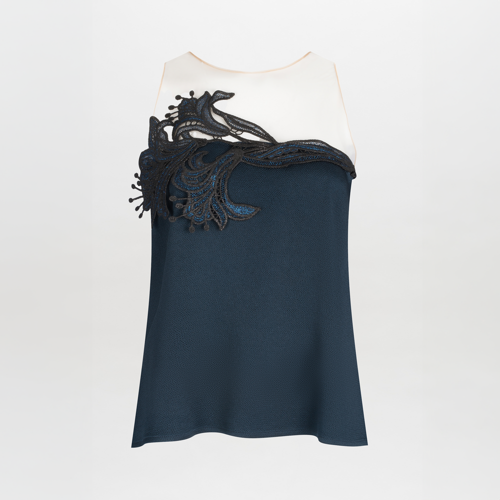 The Brisa Blouse by SVT DESIGNS is a sleeveless hammered satin top with a cream upper, dark blue lower section, and an abstract guipure lace appliqué sweeping from the left shoulder across the chest.