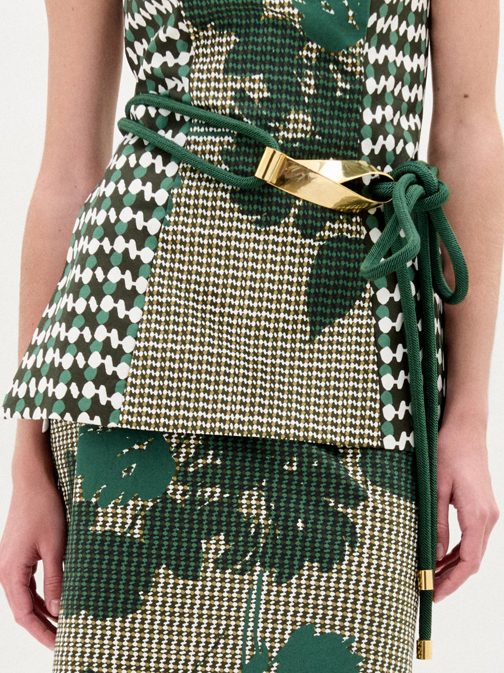 A person wears SVT DESIGNS' Daiana Belt over a patterned green, white, and gold outfit, standing against a light background.