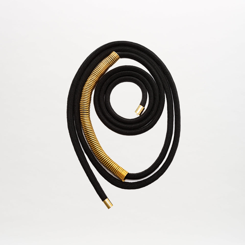 The Dunia Belt by SVT DESIGNS, crafted from fine Italian material in black with gold embellishments, is displayed in a spiral on a plain white background.