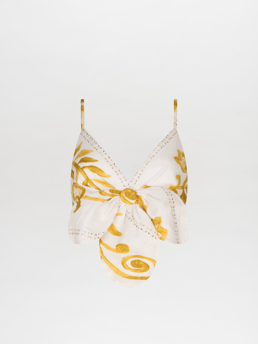 The Flor Top by Silvia Tcherassi US is a white halter top adorned with yellow floral and swirl patterns. It features 3D petal detailing, a central knot, and thin straps for an elegant look.