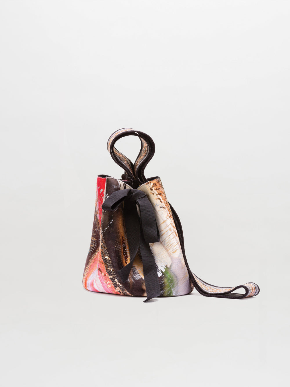 The Mochila Laaput Small by SVT DESIGNS is a small handbag with a multicolored abstract pattern, a looped handle, black ribbon detail on the side, and a thin shoulder strap, shown against a plain light background.