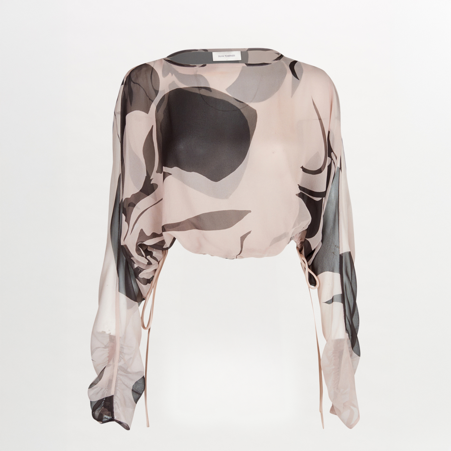 The Silvia Tcherassi Macerata Blouse is a long-sleeved, semi-sheer silk chiffon top with an abstract black, gray, and beige print. It features batwing sleeves, side drawstrings, and a loose, flowy fit.