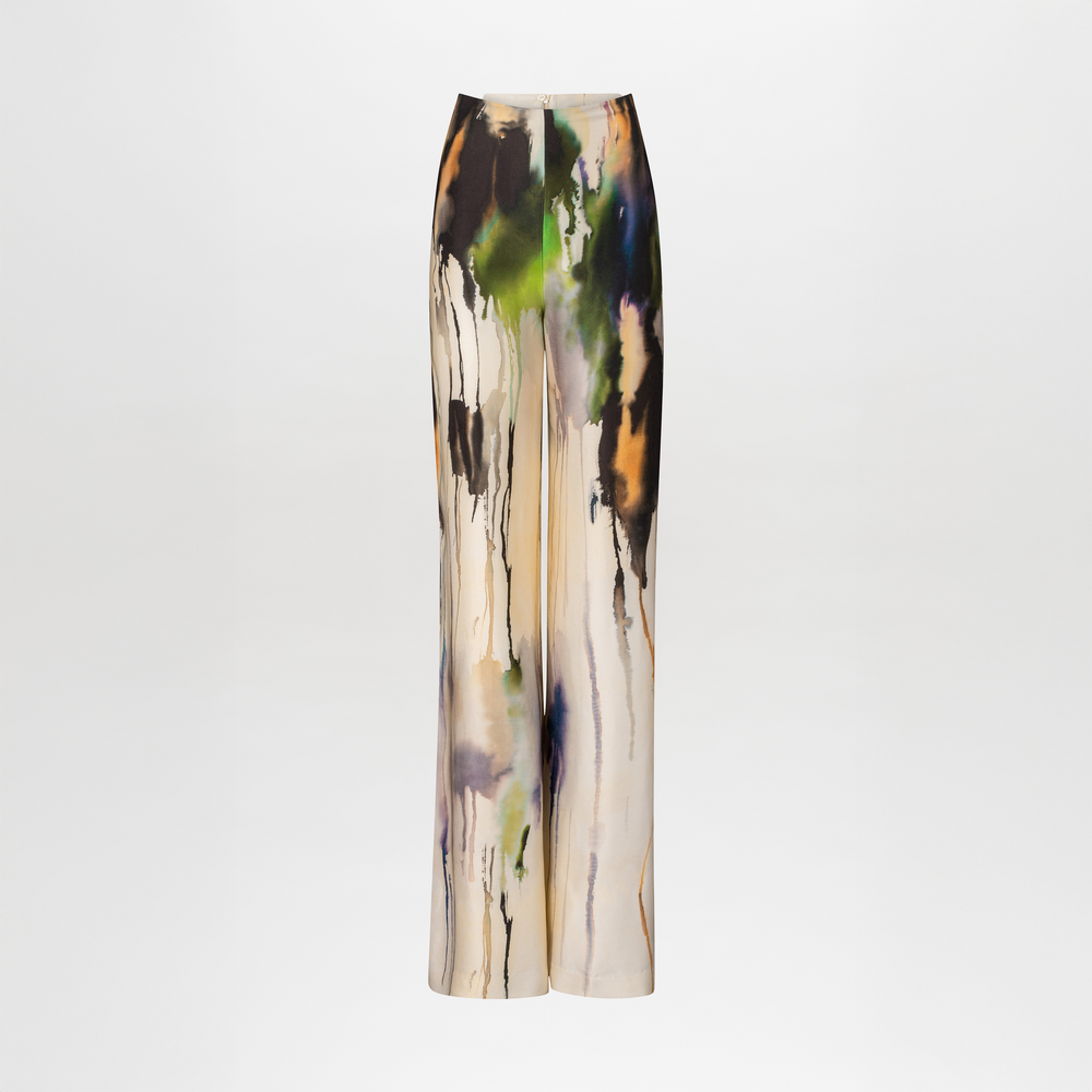The Palermo Pant by SVT DESIGNS features high-waisted, wide-leg pants with a multicolor abstract print in black, green, blue, orange, and purple on a cream backdrop.