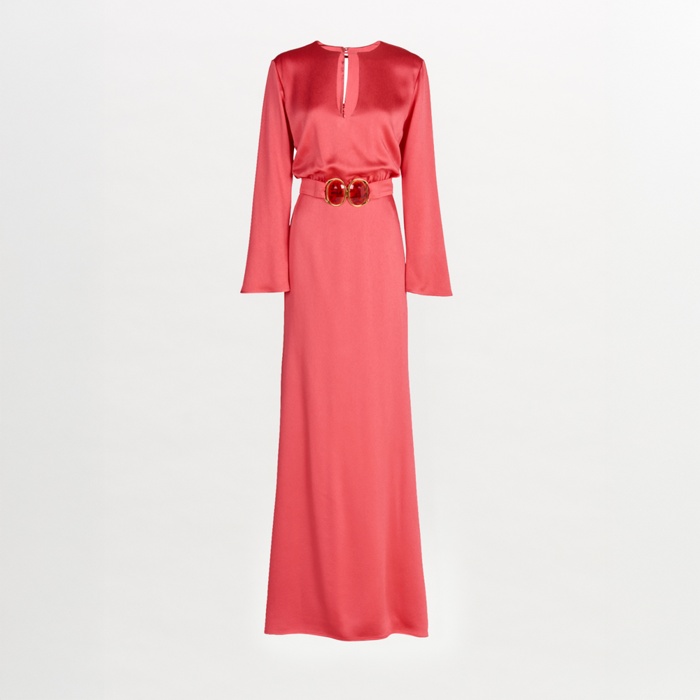 The Ravenna Dress by Silvia Tcherassi is a long-sleeved, floor-length pink hammered satin column dress with a keyhole neckline and a matching belt with a double-circle buckle at the waist.
