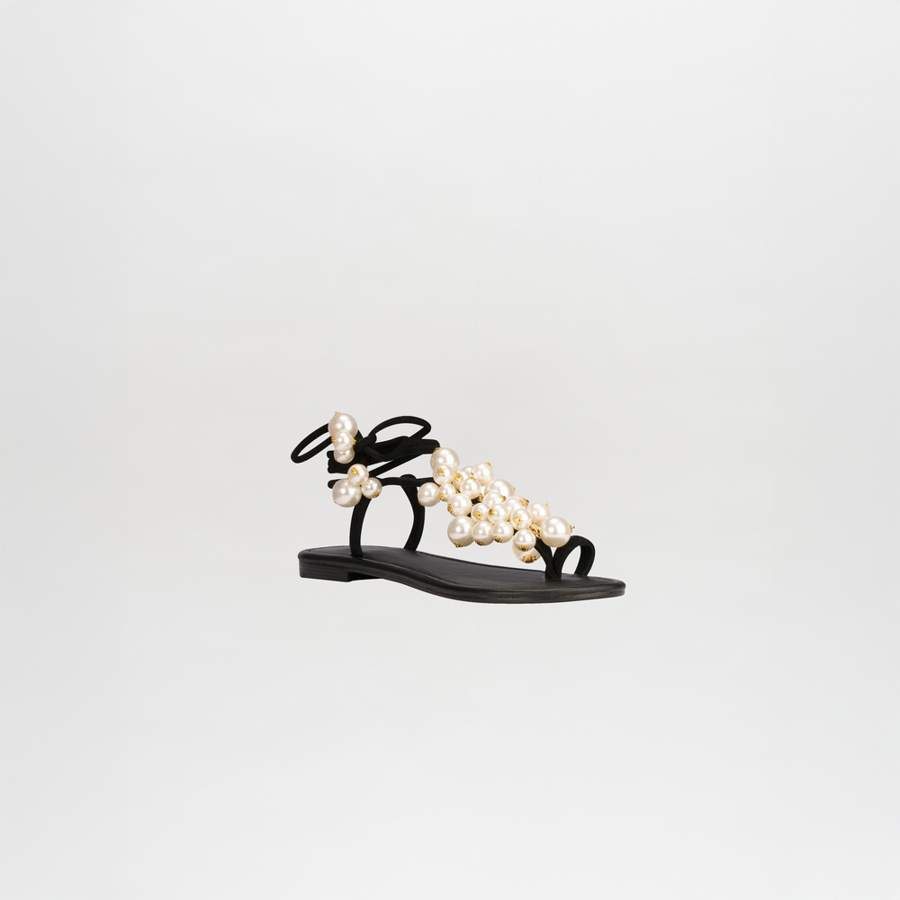 The Zaira Sandals by SVT DESIGNS feature black leather and thin wrap-around ankle straps, adorned with clustered large and small pearl embellishments, shown on a plain white background.