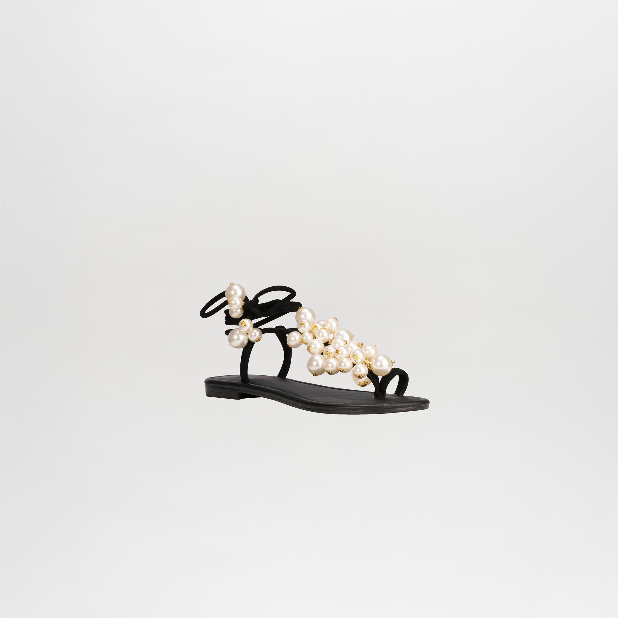 The Zaira Sandals by SVT DESIGNS feature black leather and thin wrap-around ankle straps, adorned with clustered large and small pearl embellishments, shown on a plain white background.