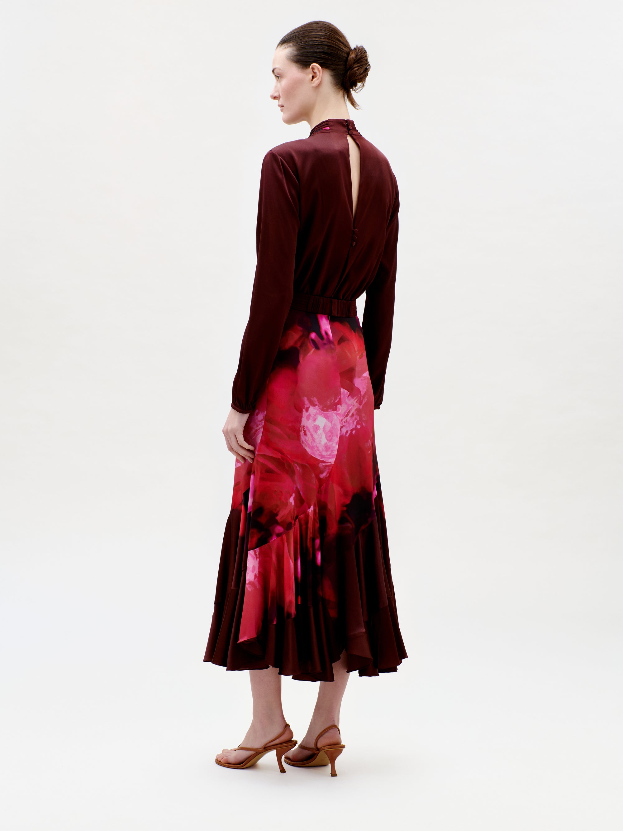 Woman wearing a burgundy dress with a red floral pattern on a white background