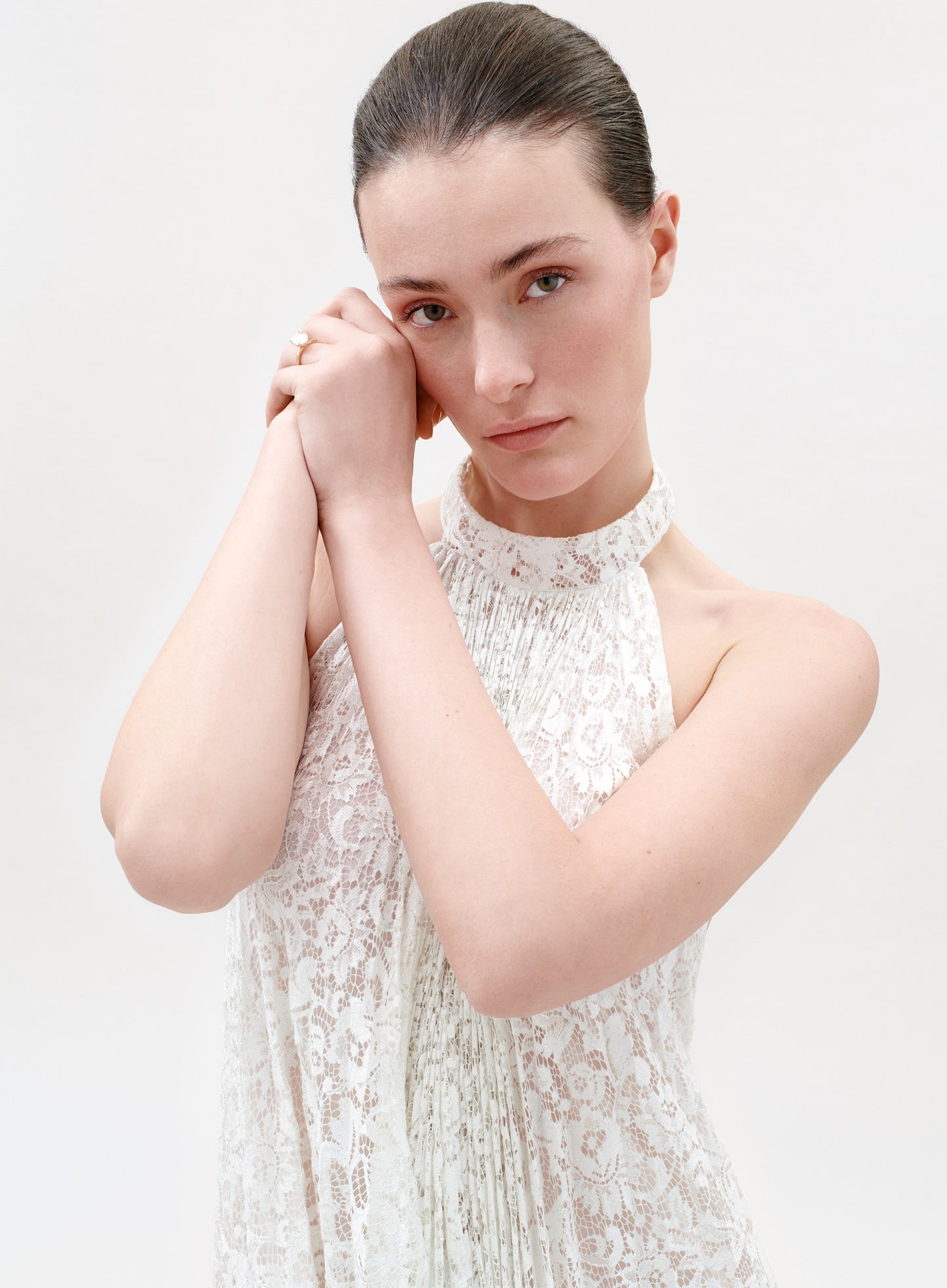 Woman wearing a white lace dress against a plain background