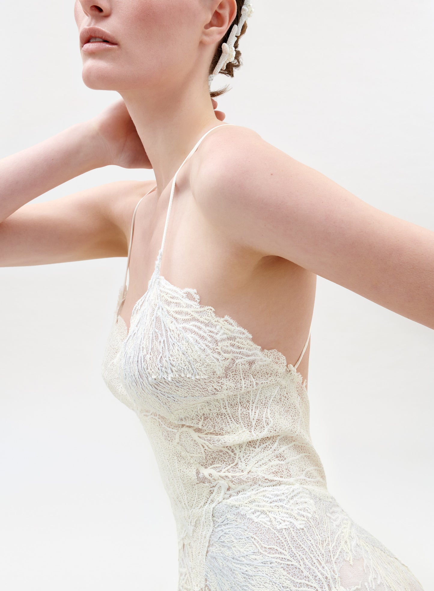 Close-up of a person wearing a white lace dress against a light background