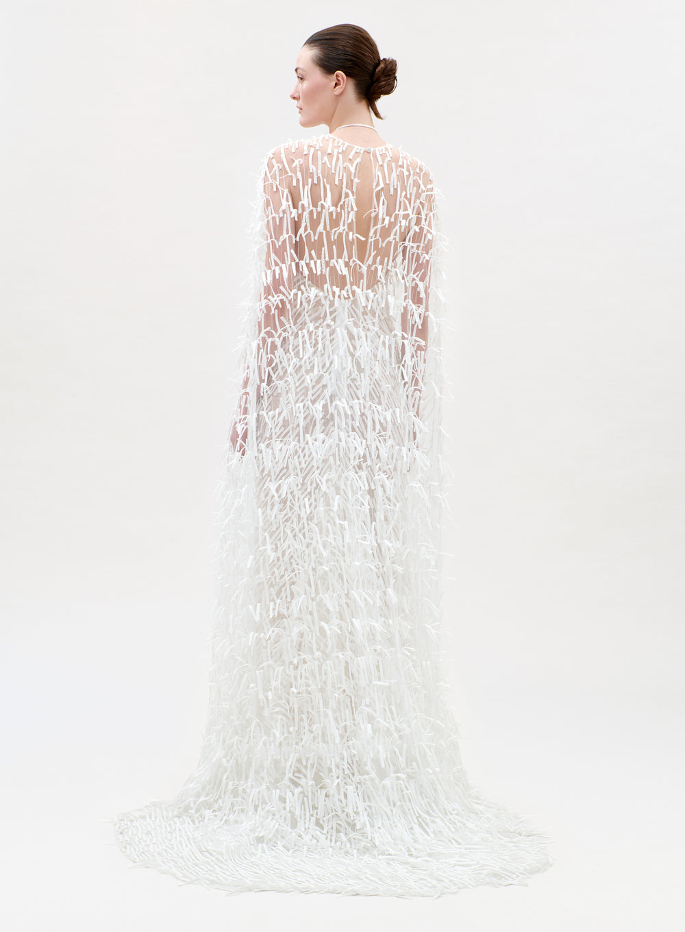Woman wearing a long, white, textured dress on a light gray background
