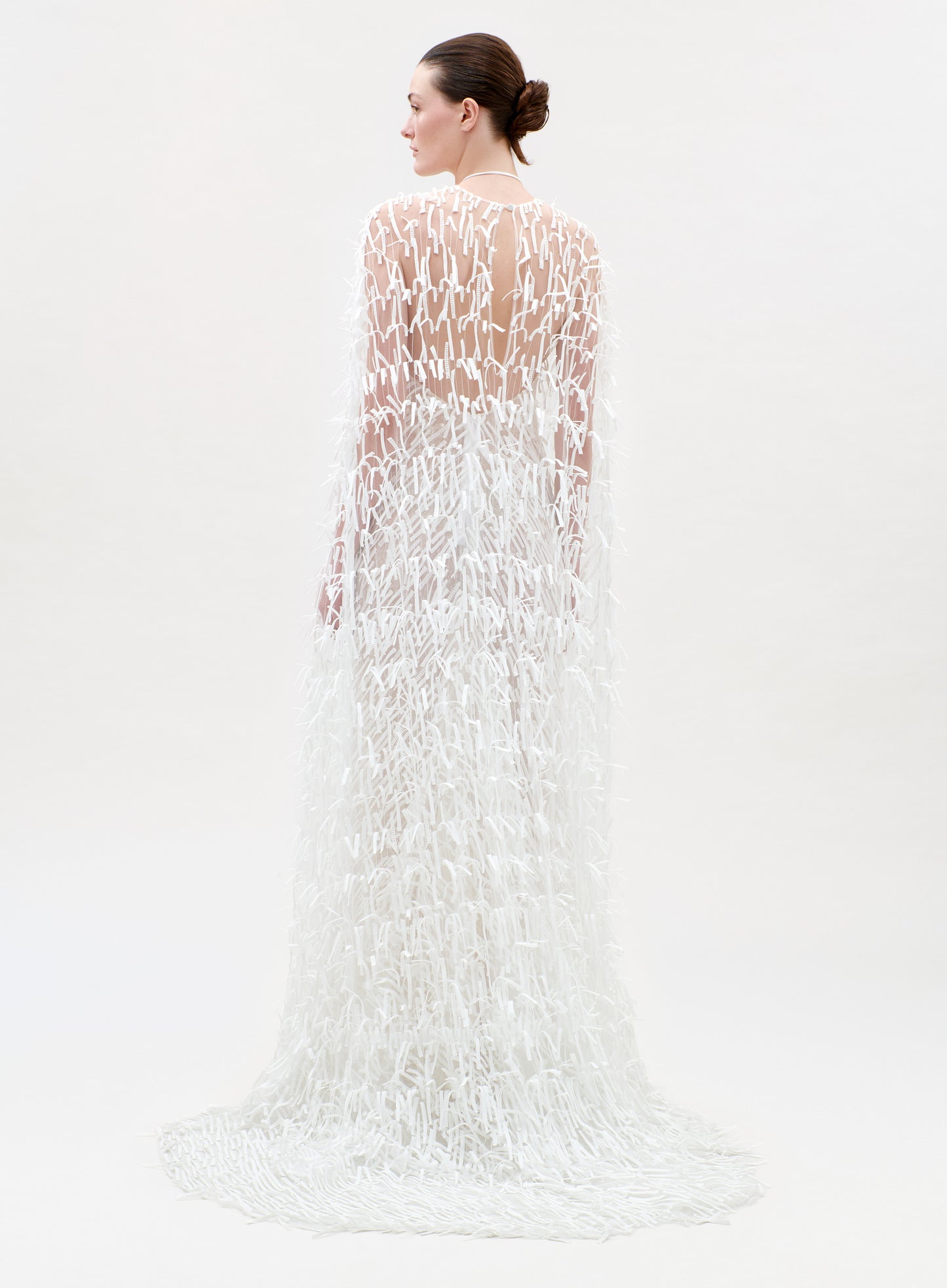 Woman wearing a long, white, textured dress on a light gray background