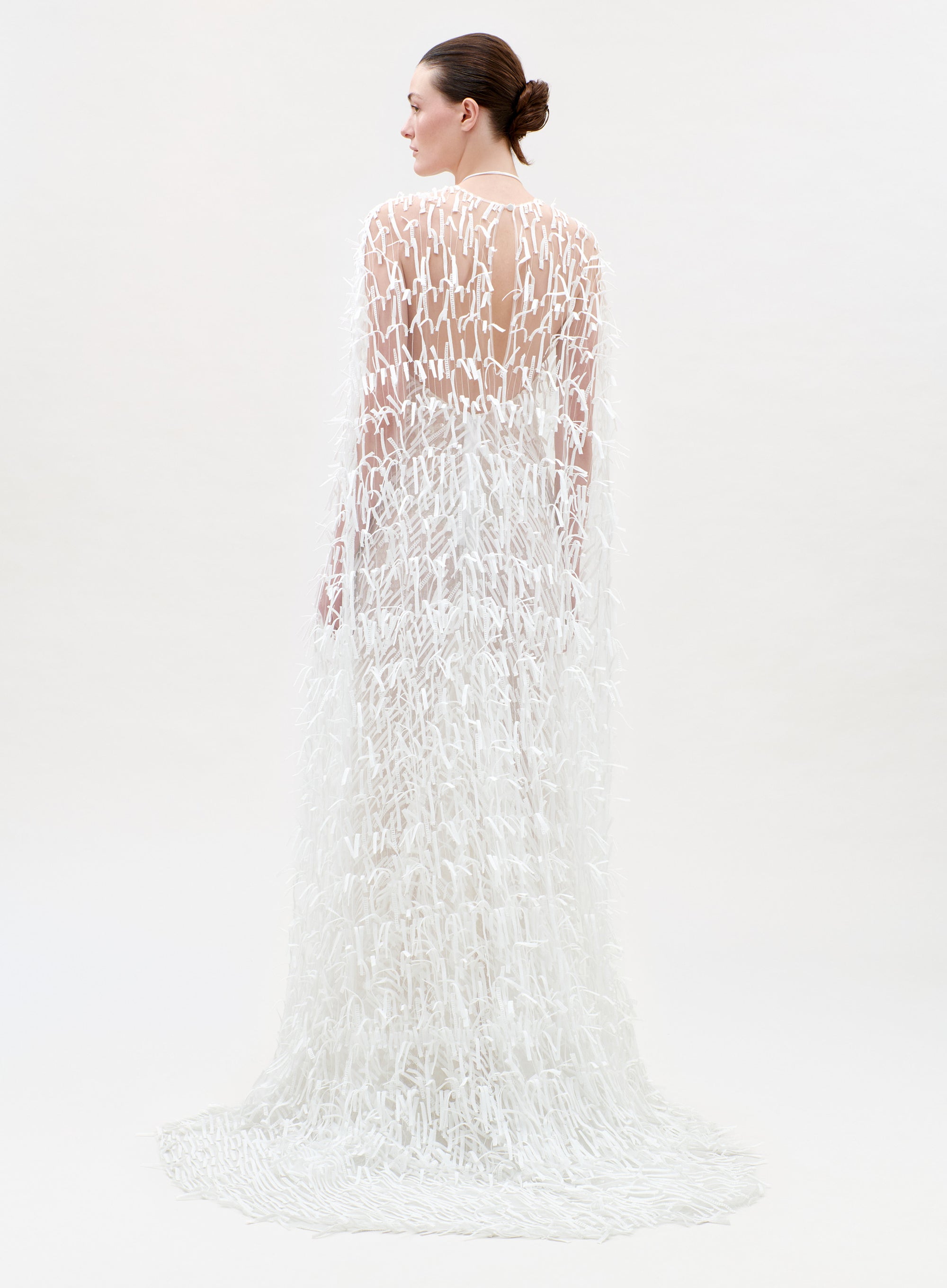 Woman wearing a long, white, textured dress on a light gray background