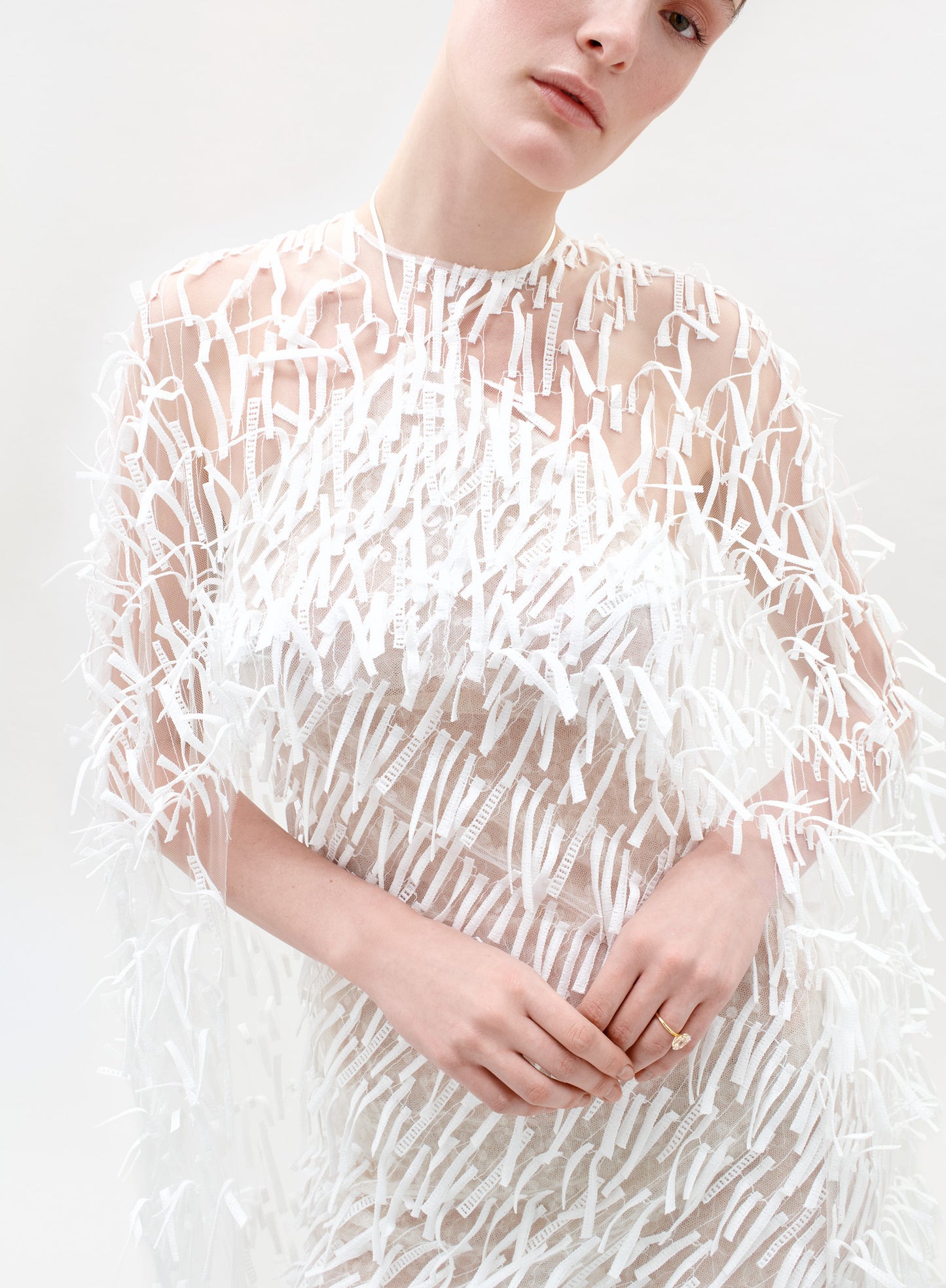 Woman wearing a long, white, textured dress on a light gray background