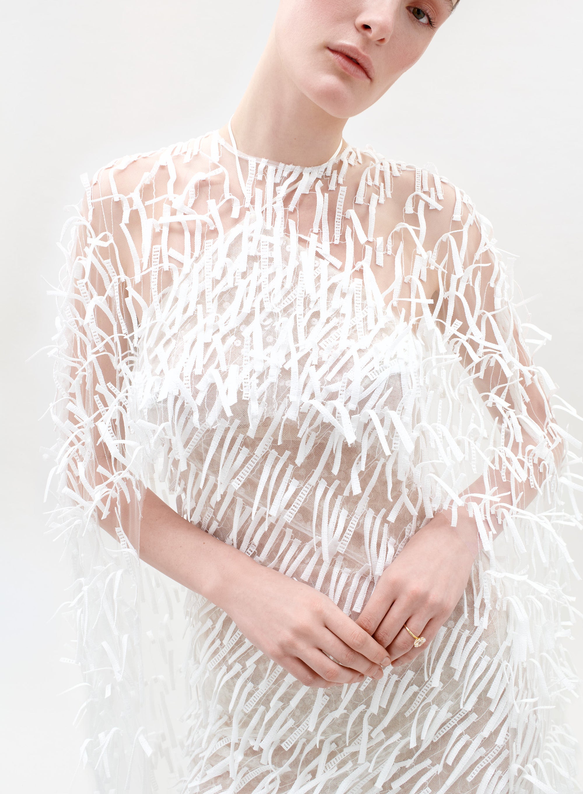 Woman wearing a long, white, textured dress on a light gray background