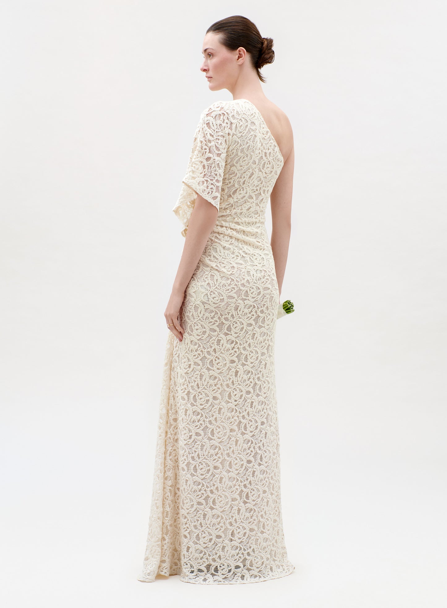 Woman wearing a long, off-white lace dress on a white background
