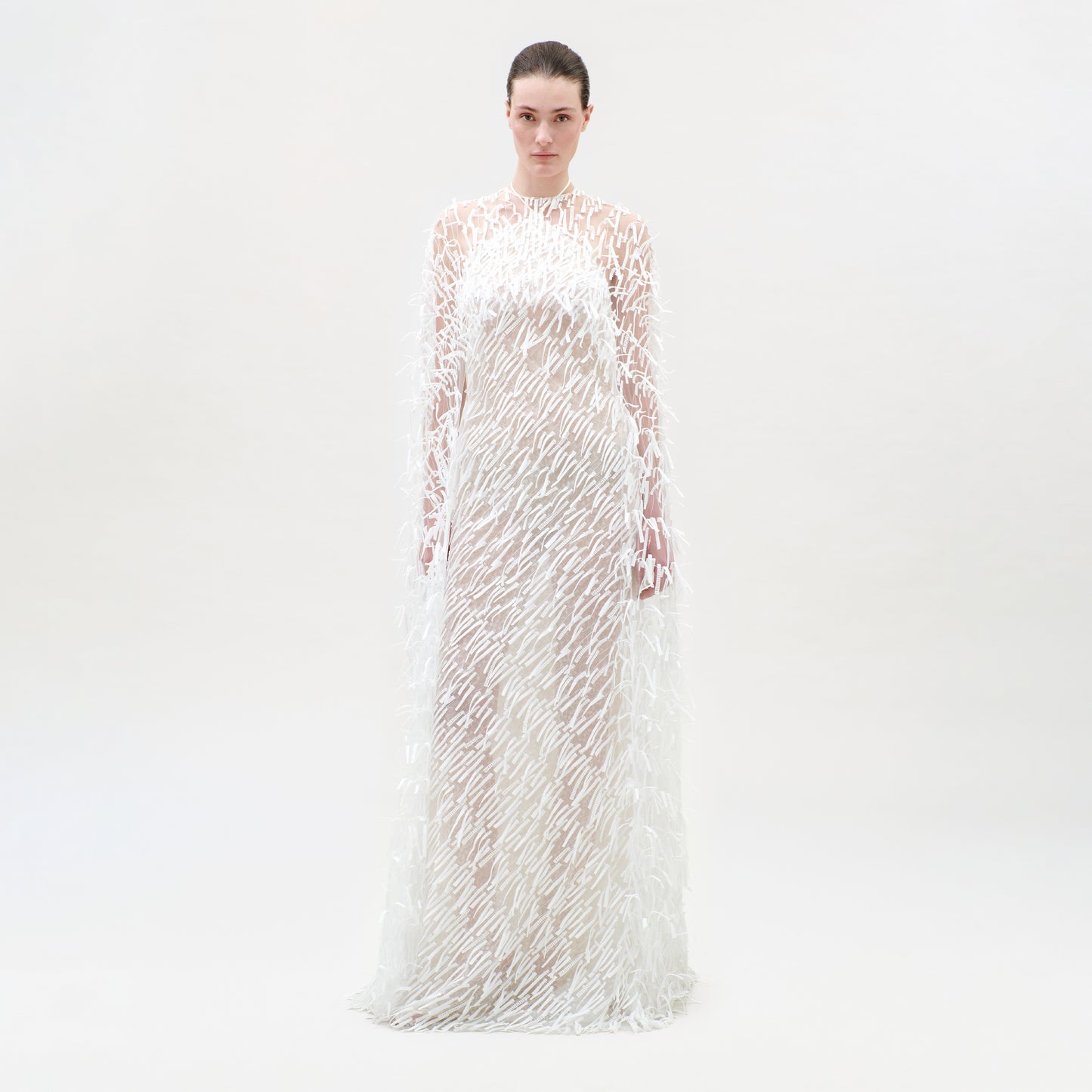 Woman wearing a long, sheer dress with floral patterns on a white background