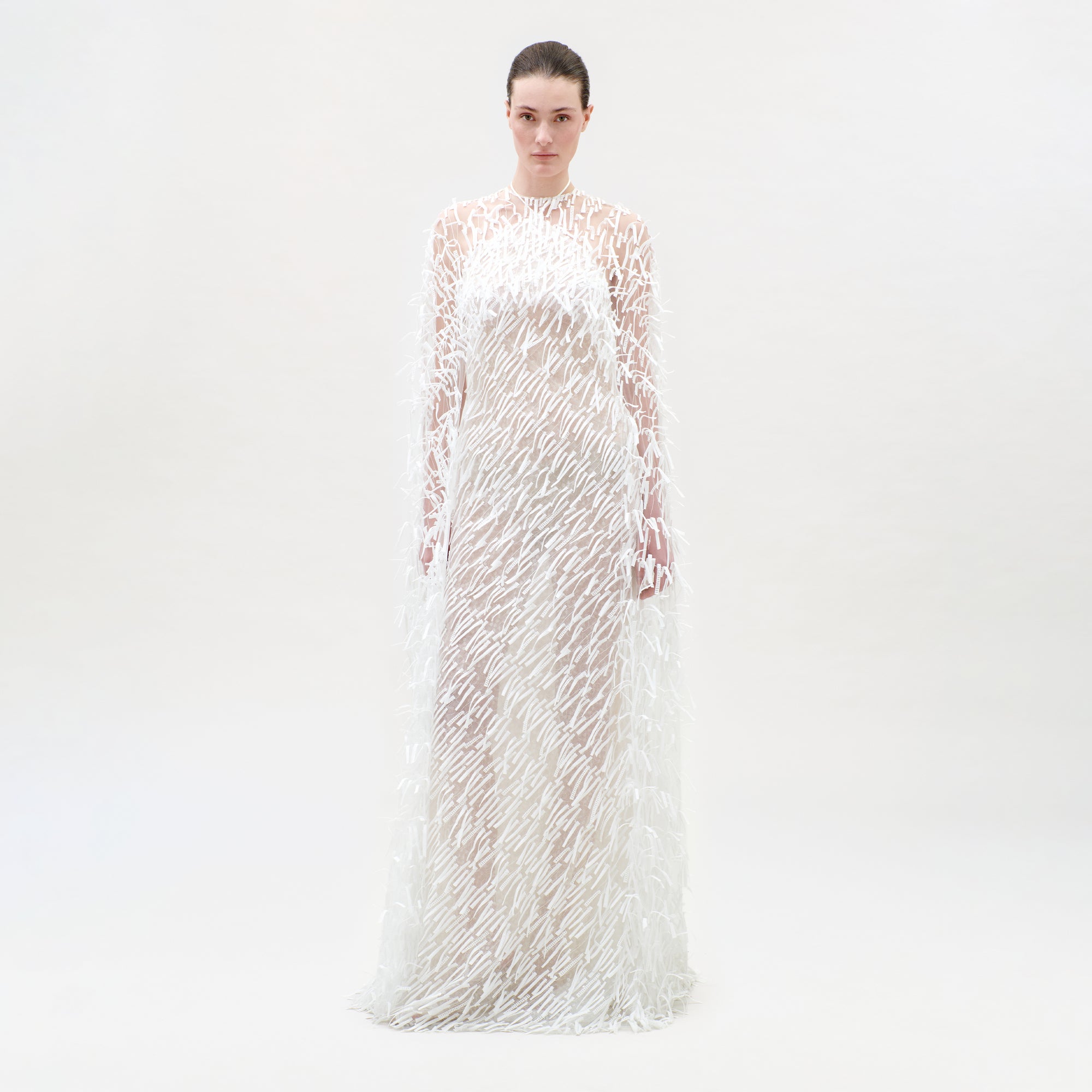 Woman wearing a long, sheer dress with floral patterns on a white background