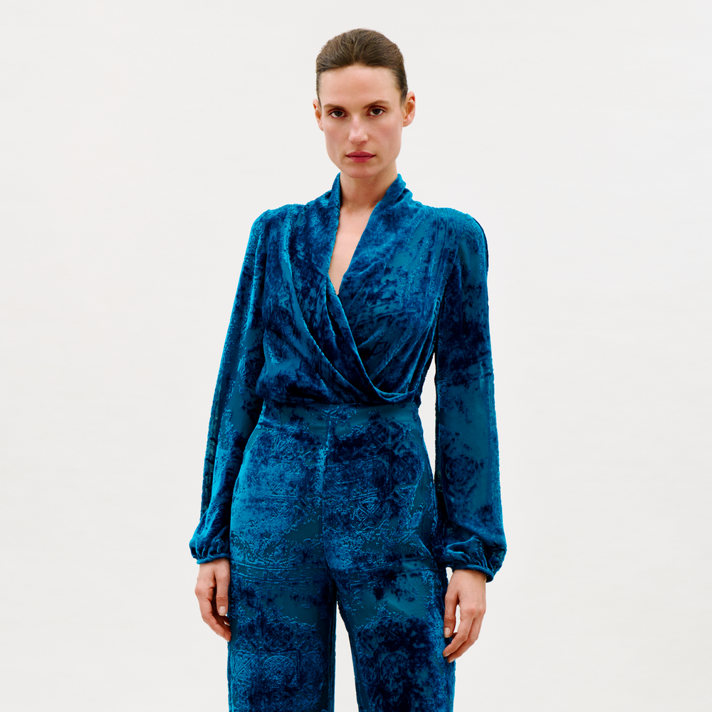 Woman wearing a blue velvet jumpsuit on a white background