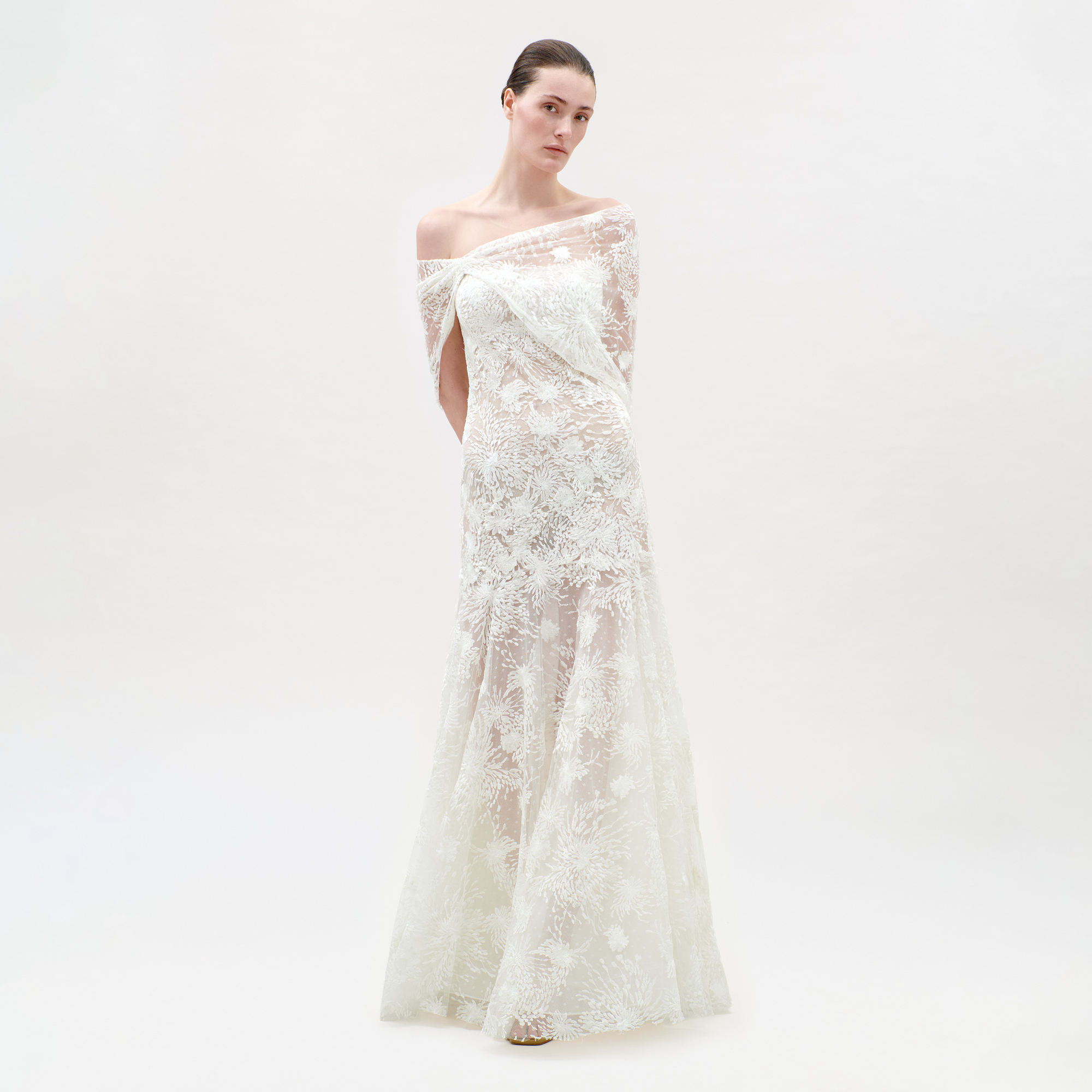 Woman wearing a white lace dress on a plain background
