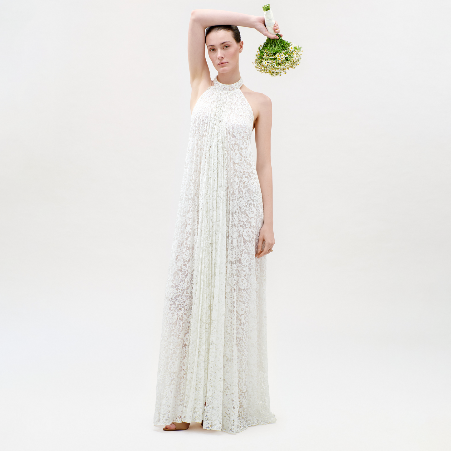 Woman wearing a white lace dress holding a bouquet on a white background