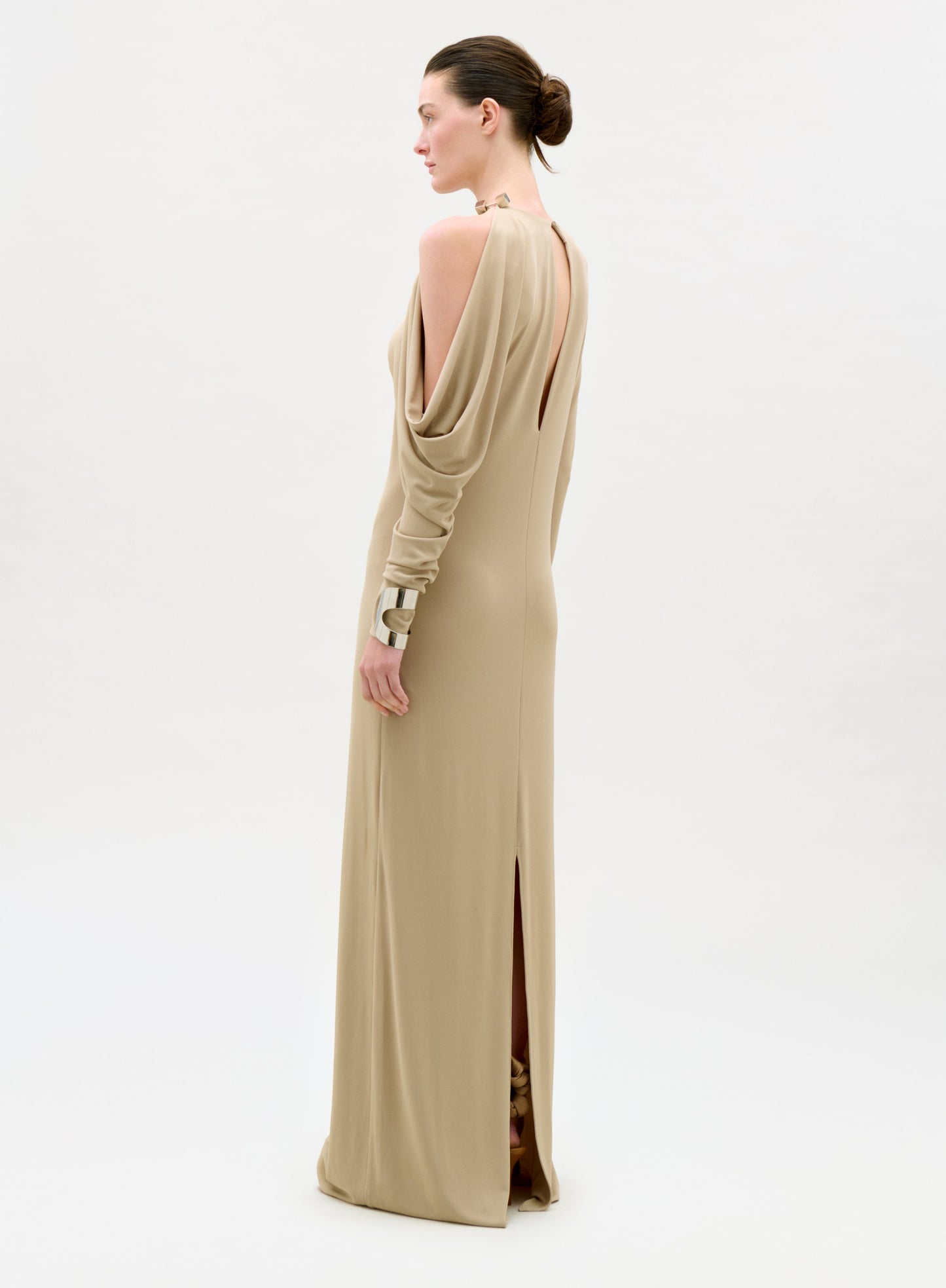 Woman wearing a beige evening gown with a high slit on a white background