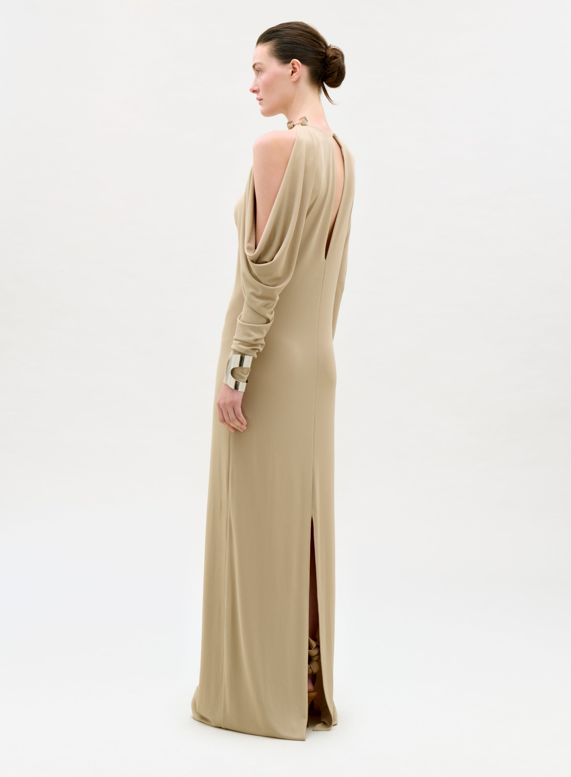 Woman wearing a beige evening gown with a high slit on a white background