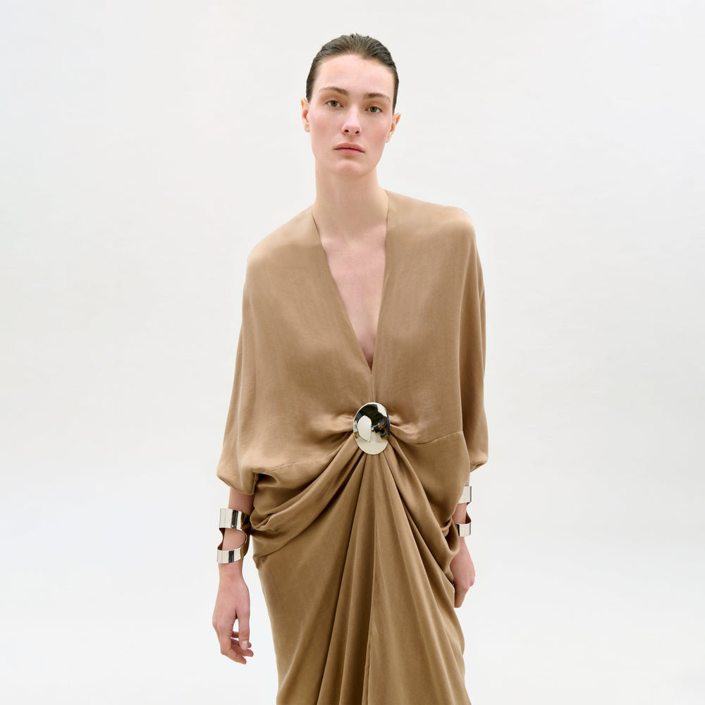Woman wearing a beige dress with a large bow detail on a white background