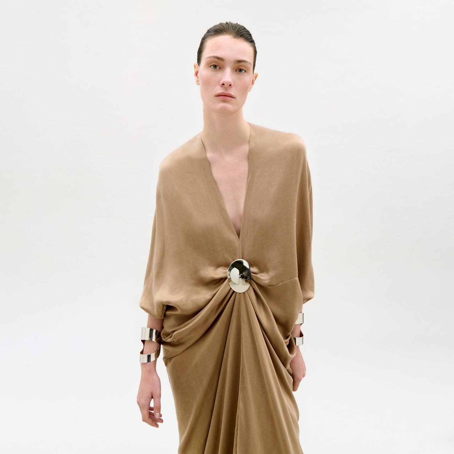 Woman wearing a beige dress with a large bow detail on a white background