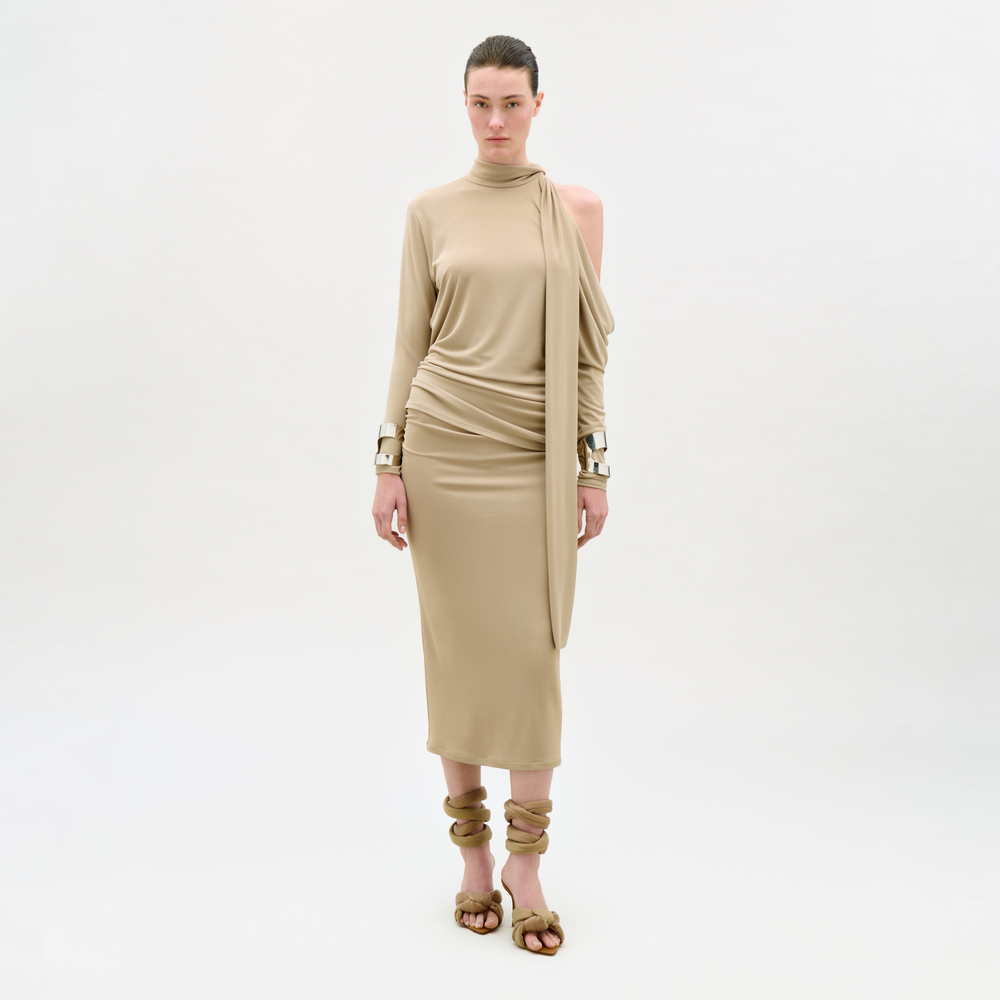 Woman wearing a beige dress with cut-out shoulders on a white background