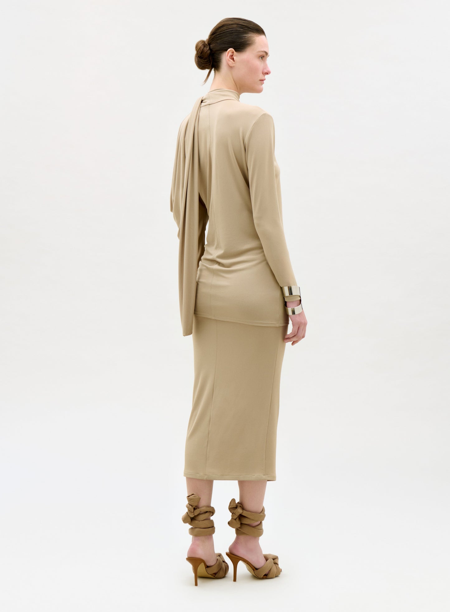 Woman wearing a beige dress with a matching jacket on a white background