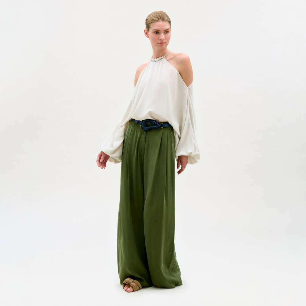 Woman wearing a white top and green pants on a white background