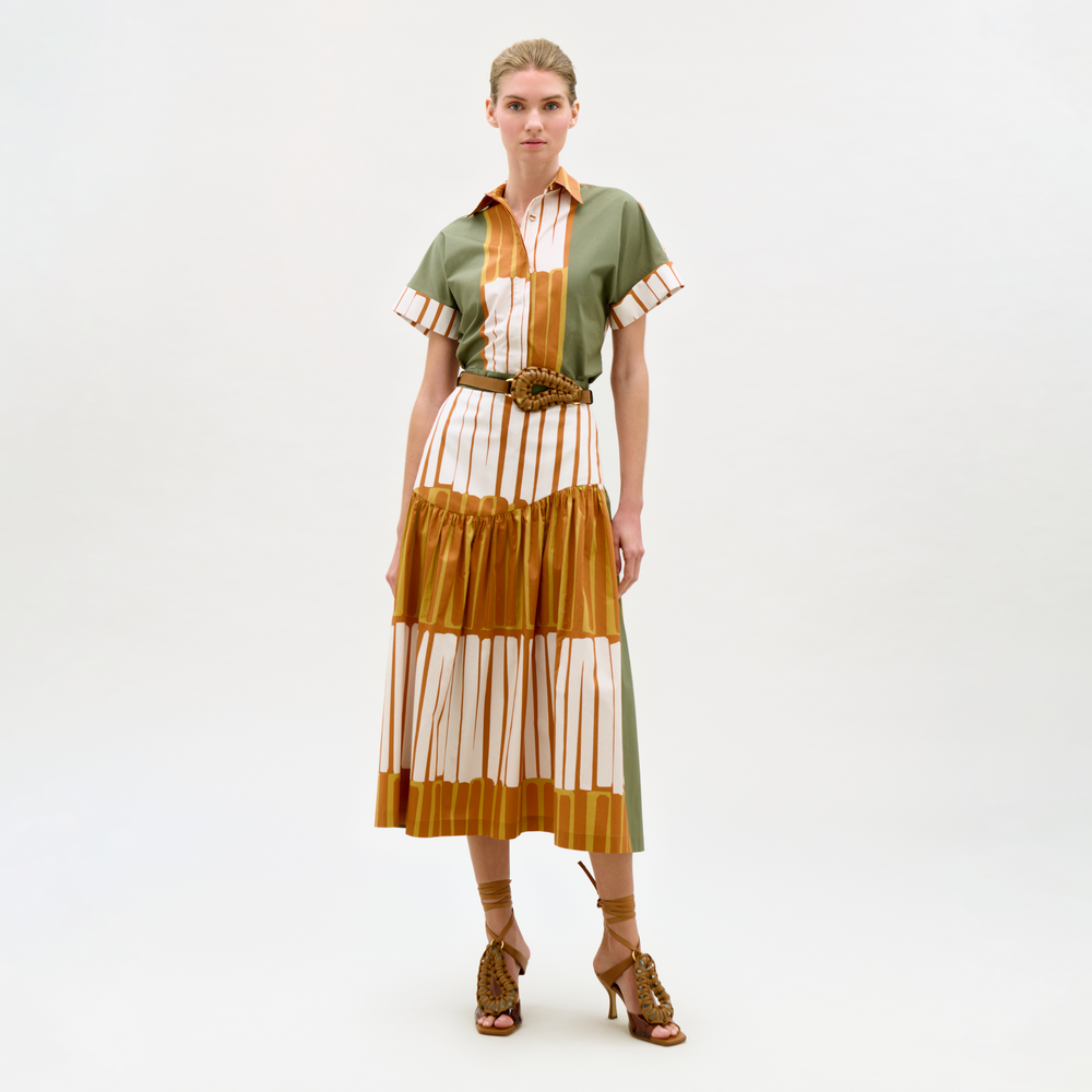 Woman wearing a green and brown striped dress with a belt on a white background