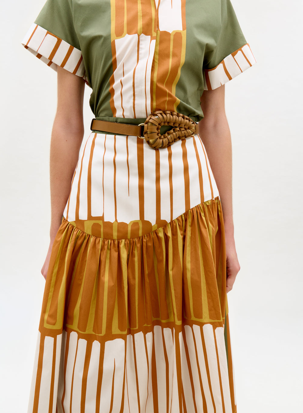 Woman wearing a green and brown striped dress with a belt on a white background
