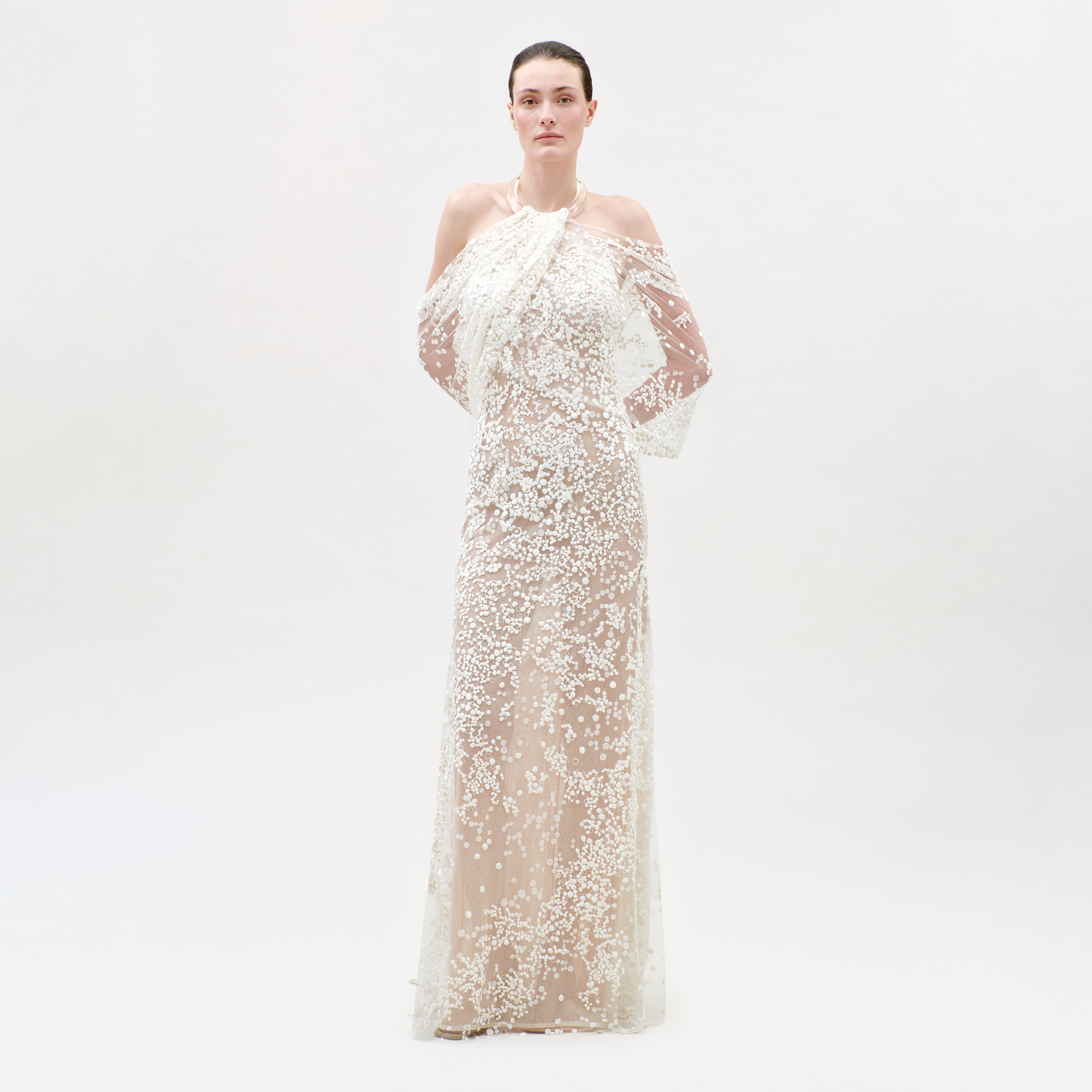 Woman wearing a long, white, textured dress on a light gray background