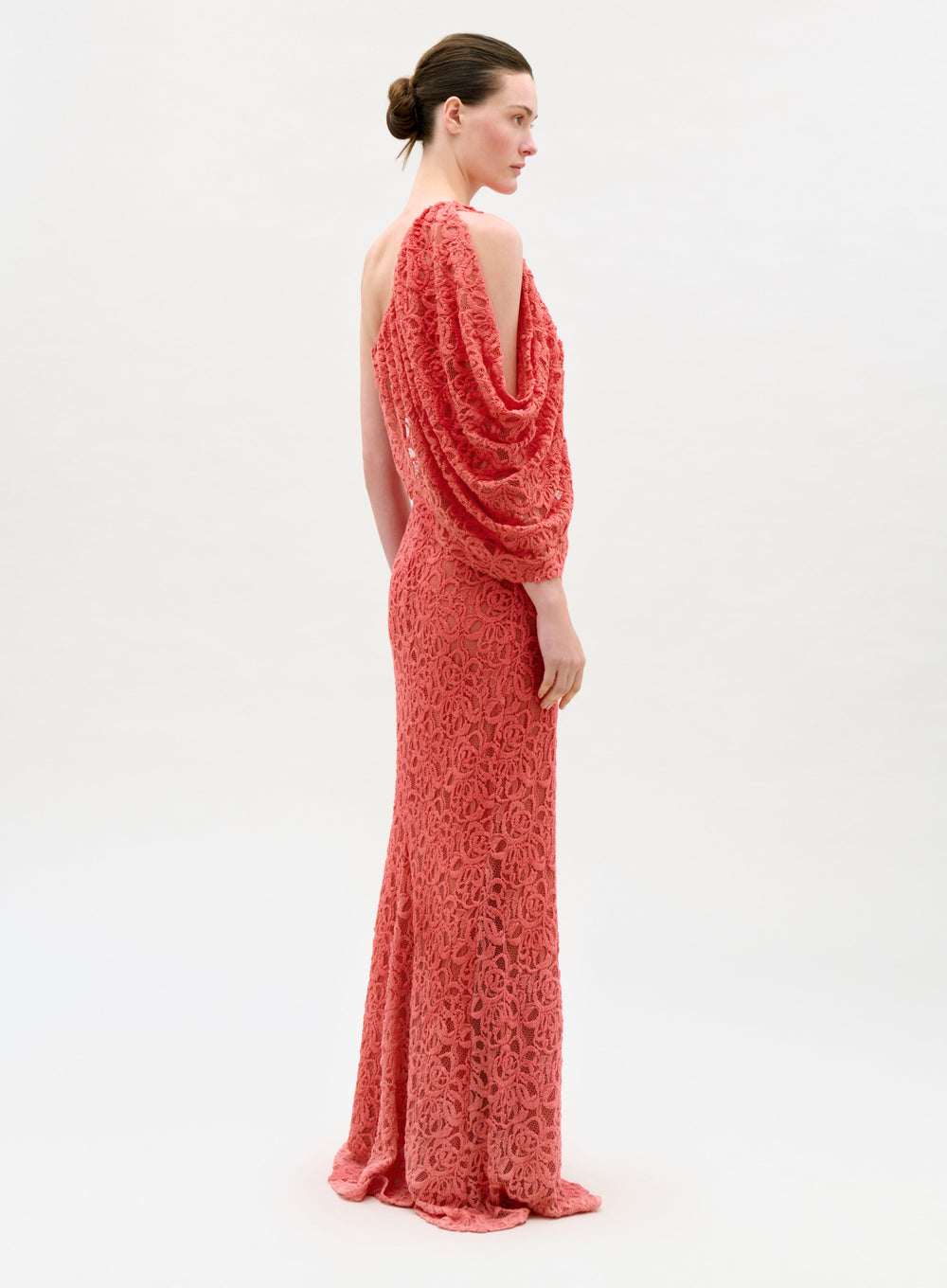 Woman wearing a coral one-shoulder evening gown on a white background
