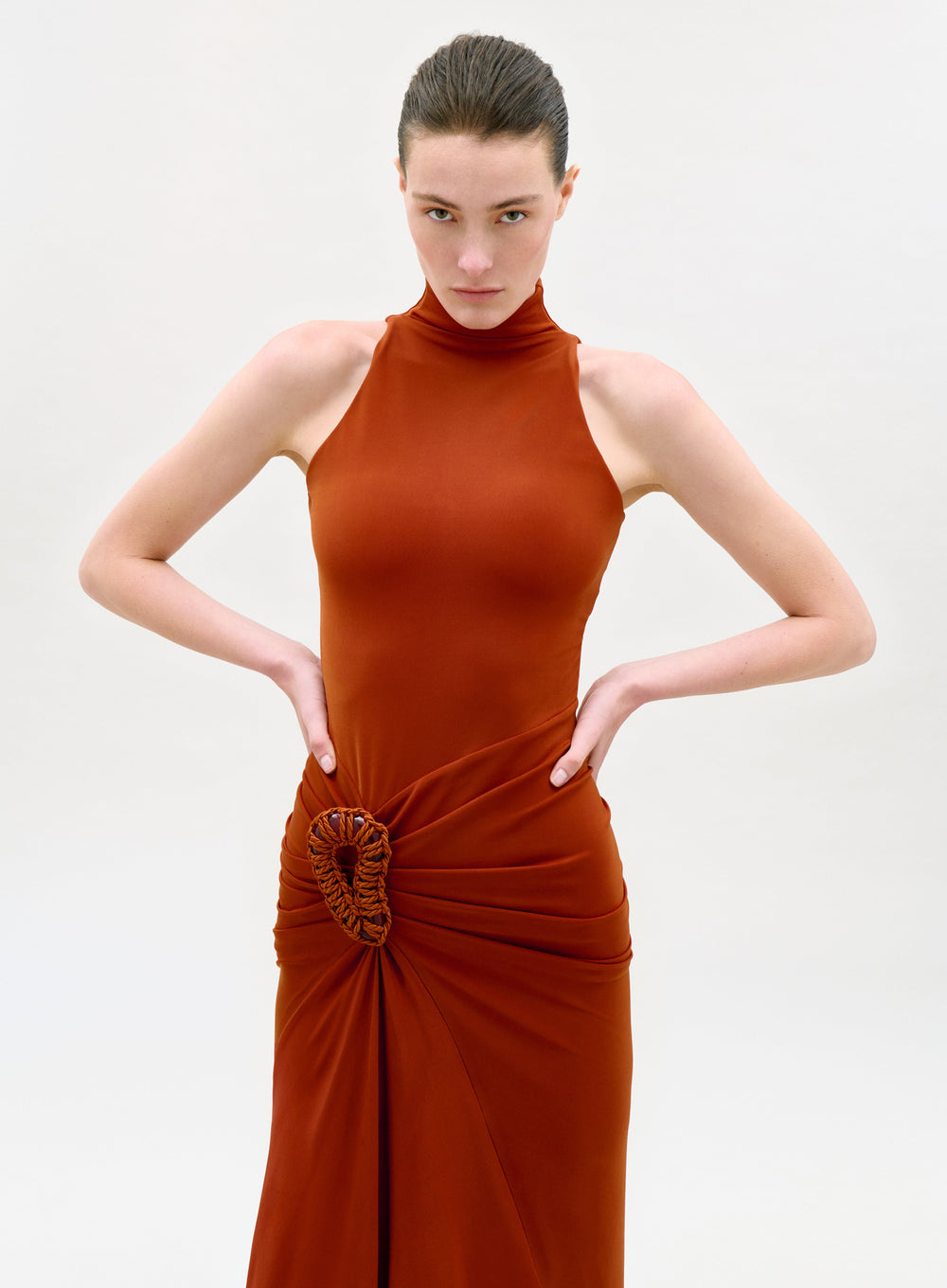 Woman wearing a rust-colored halter neck dress on a white background