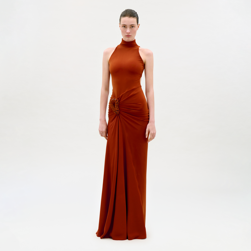 Woman wearing a rust-colored evening gown on a light gray background