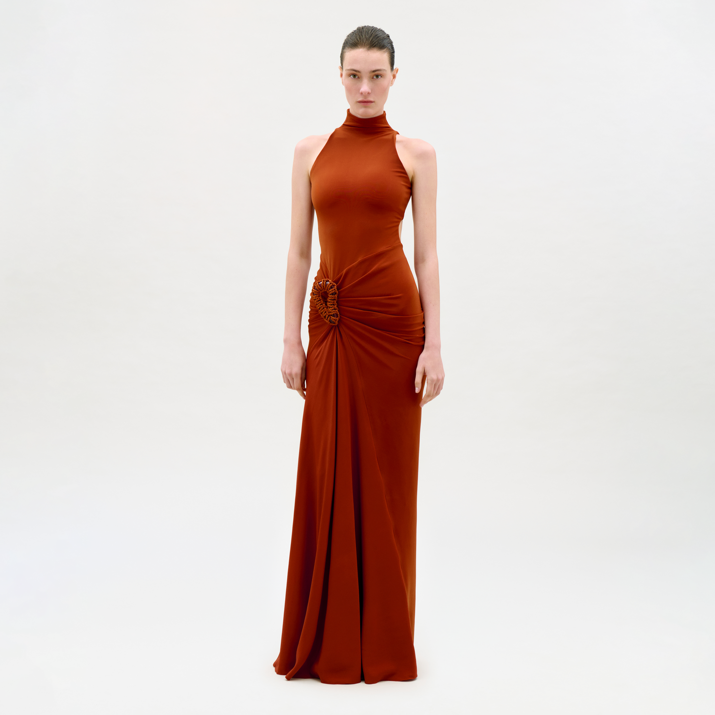 Woman wearing a rust-colored evening gown on a light gray background