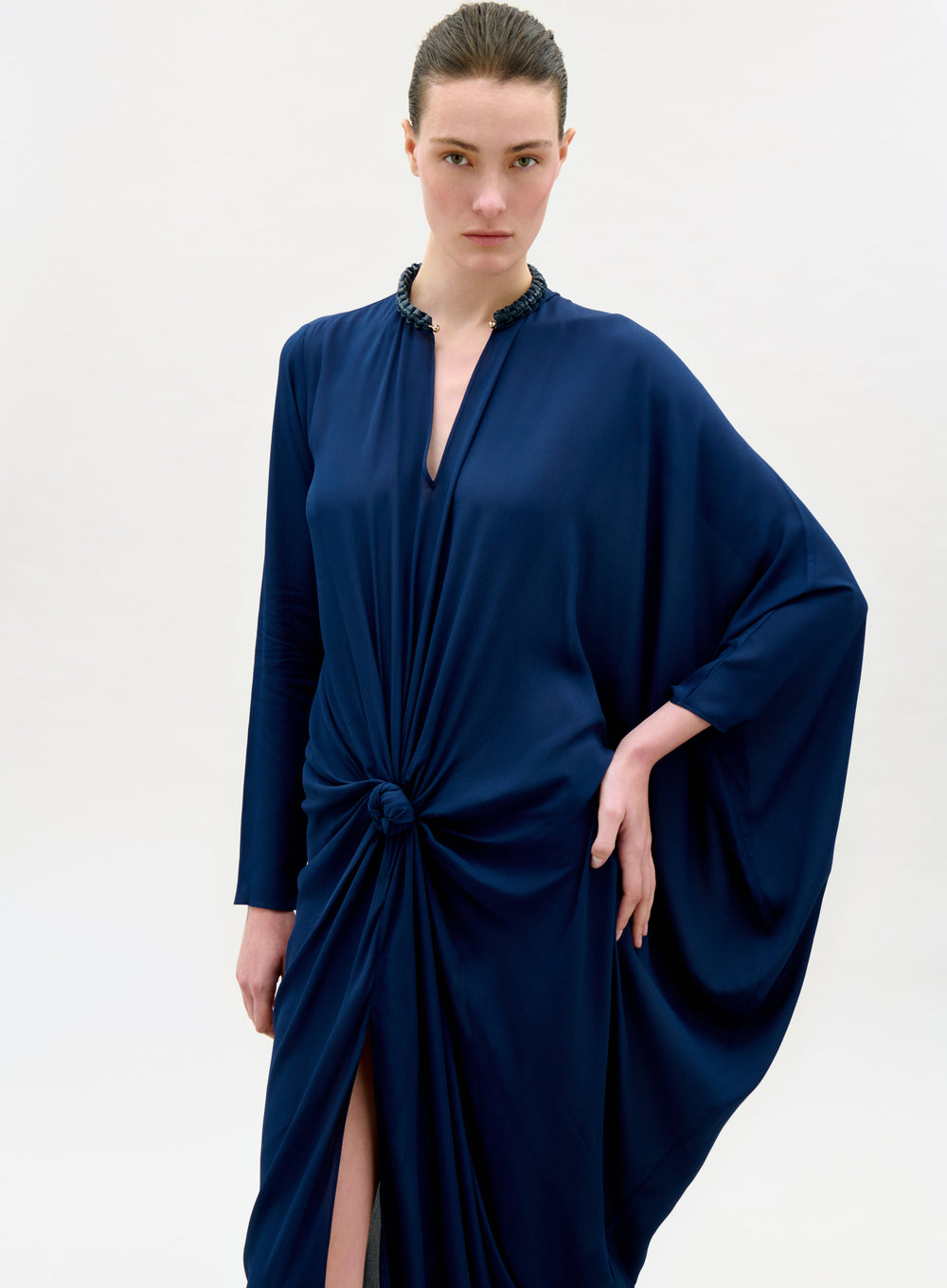 Woman wearing a navy blue dress with a knot detail on a white background