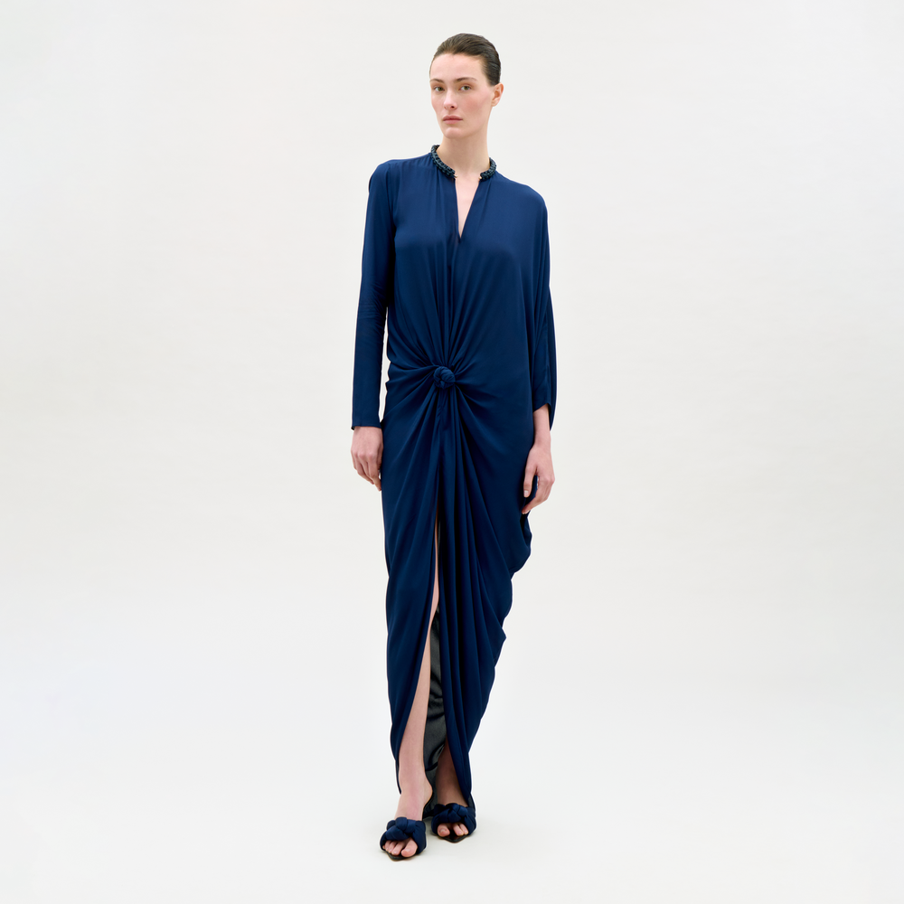 Woman wearing a blue dress with a knot detail on a white background